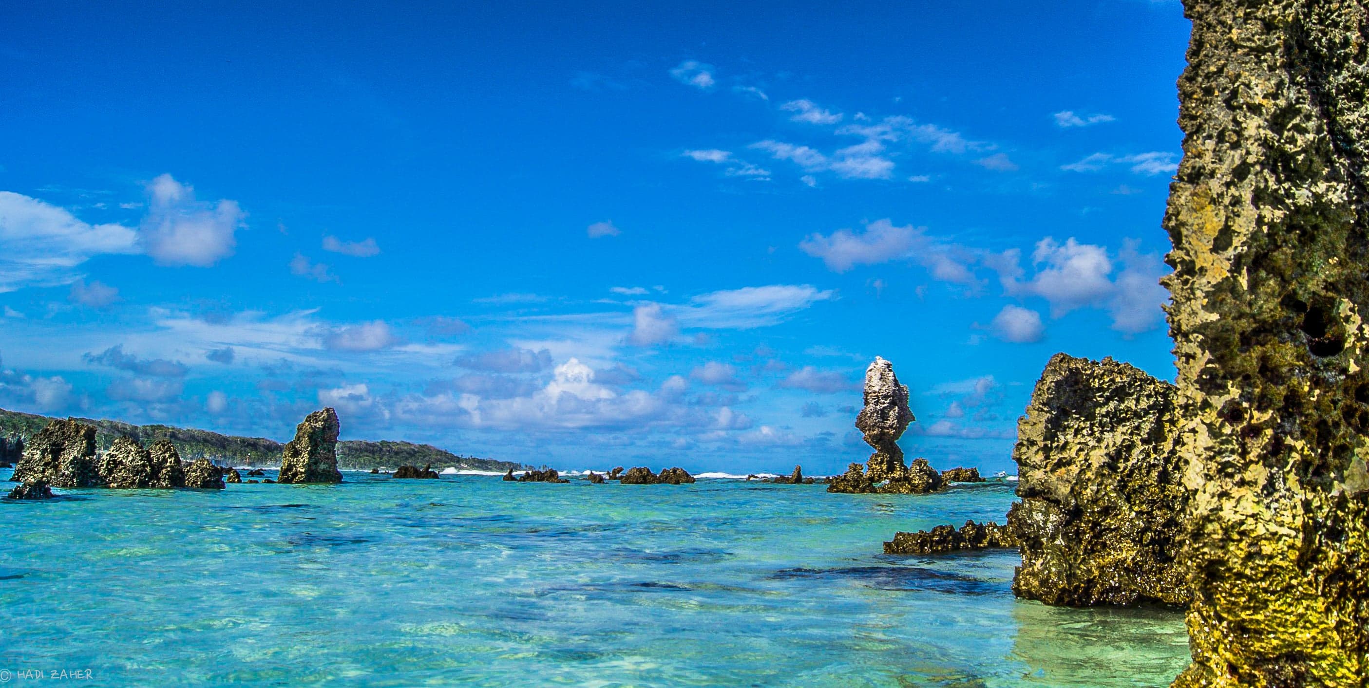 A wide sandy beach curving around calm turquoise water in Anibare Bay, Nauru