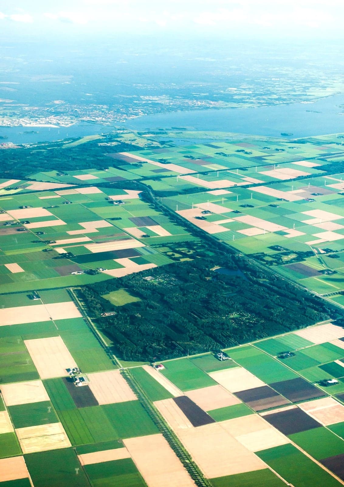 An aerial view of a flat green Dutch polder with straight canals