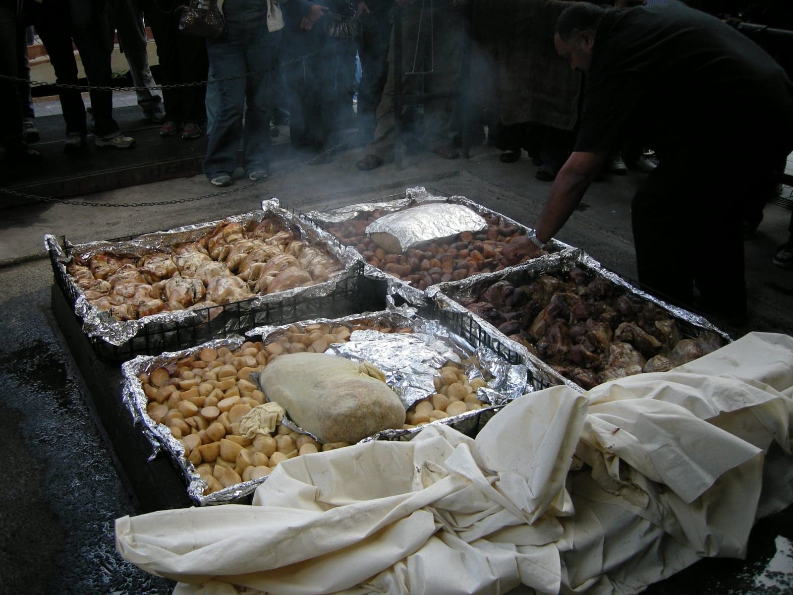 Trays of meat and vegetables being prepared after cooking in an earth oven (hāngī)