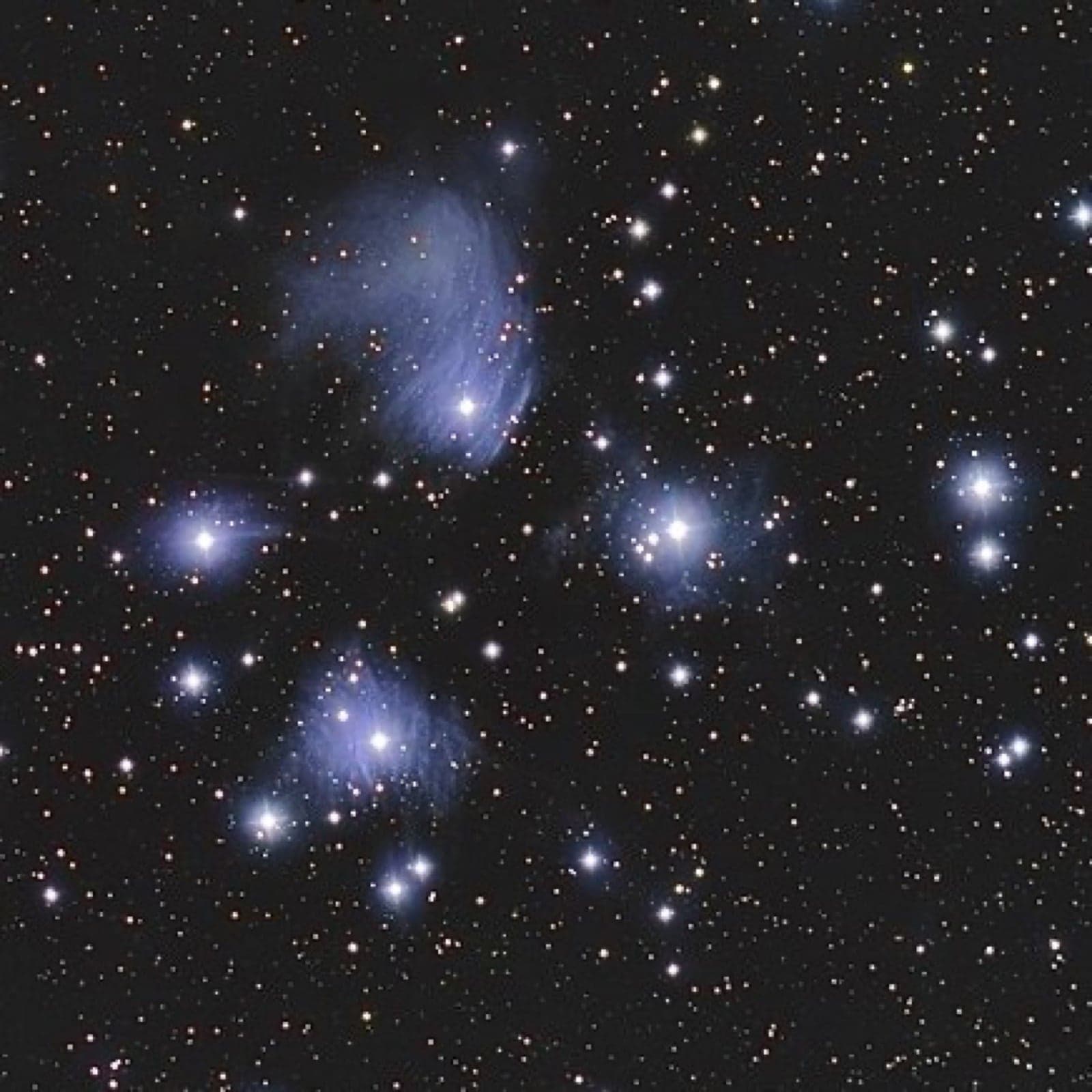 A cluster of bright blue stars surrounded by faint nebulous gas - the Pleiades / Matariki
