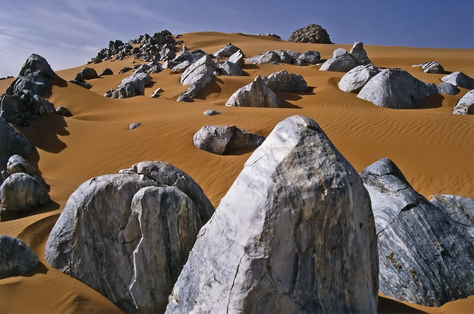Vast golden sand dunes of the Ténéré desert meeting the rocky Aïr Mountains