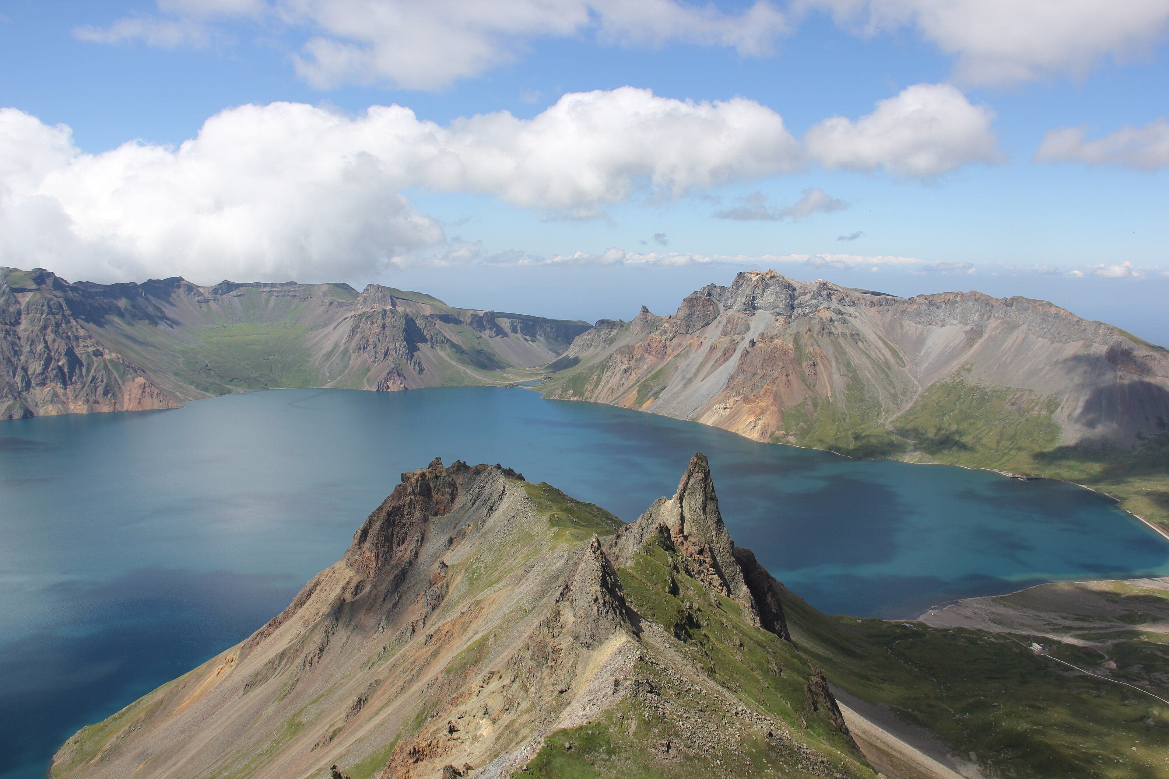 Mount Paektu volcano with the bright blue Lake Chon filling its crater, surrounded by snow