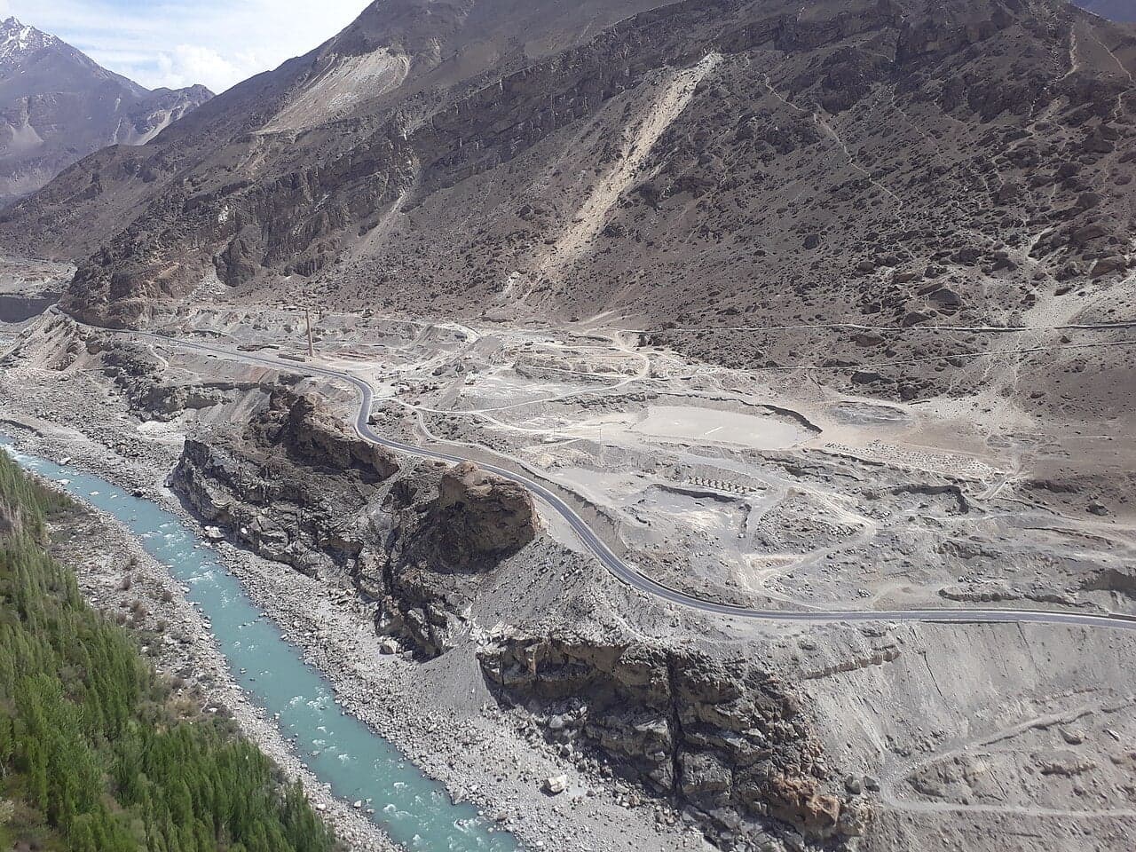 The Karakoram Highway winding through grey mountains alongside a turquoise river