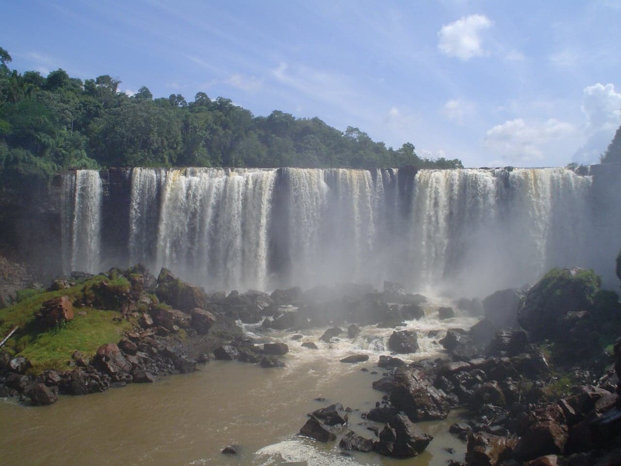 Wide cascades of white water at Ñacunday Falls surrounded by green forest