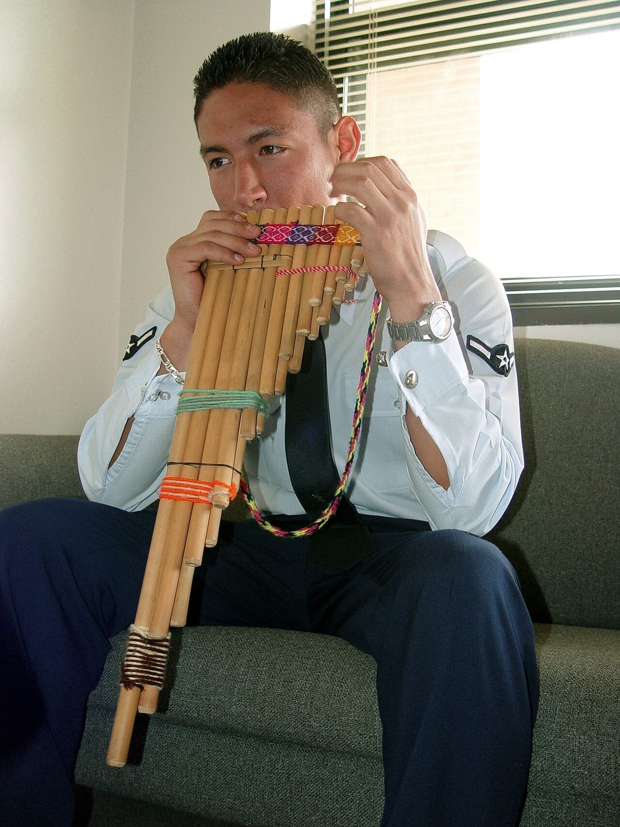 A musician holding a set of Andean panpipes to play