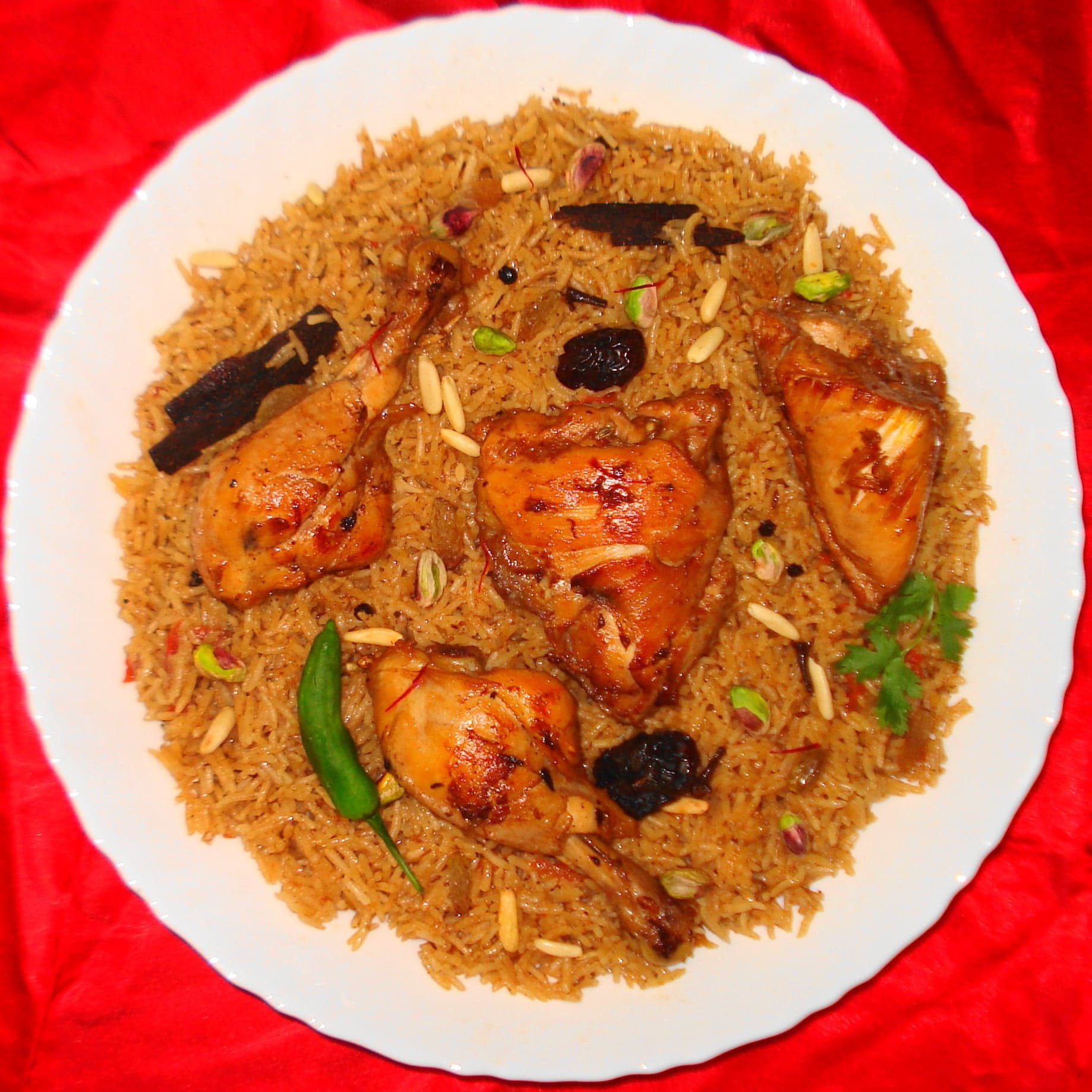 A large platter of golden machbous rice with pieces of tender lamb and raisins on top