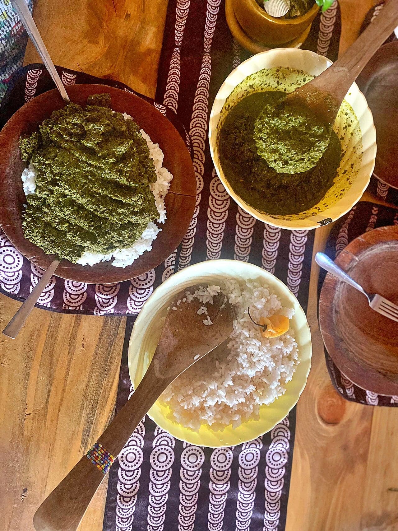 A bowl of bright green isombe stew made from cassava leaves and peanuts