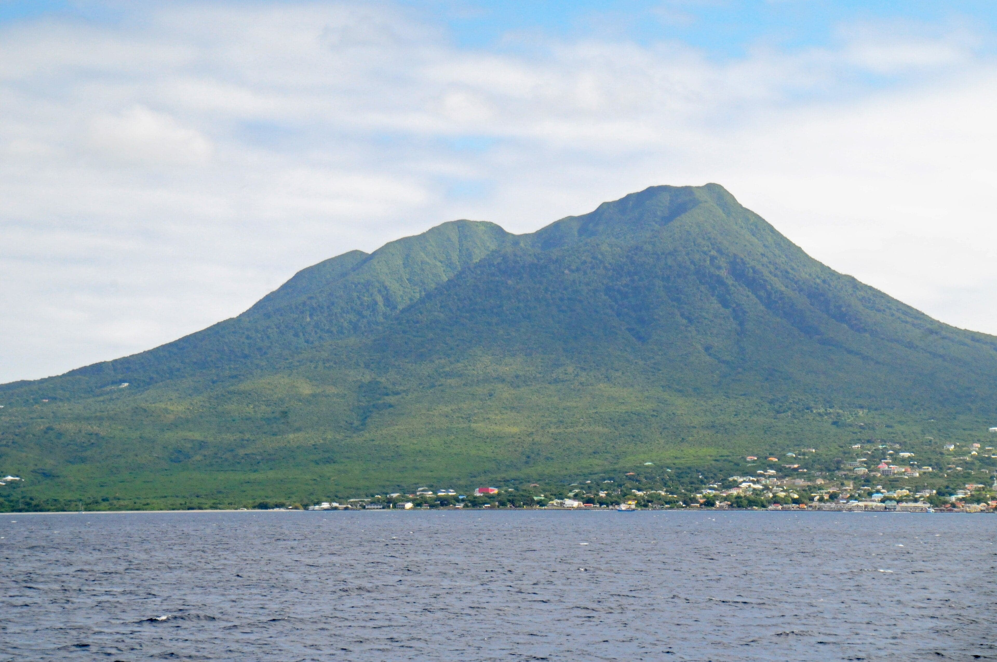 The perfectly cone-shaped Nevis Peak rising above green farmland with cloud at its tip