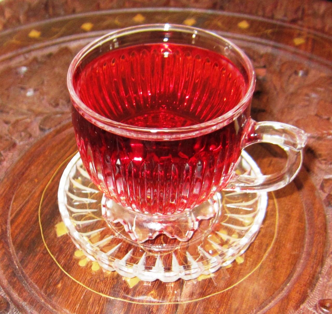 A glass of bright red sorrel drink with ice and a lime slice