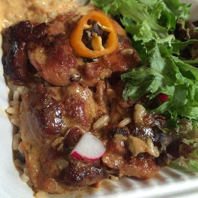 A one-pot dish of brown caramelised rice with pigeon peas, vegetables and chunks of meat