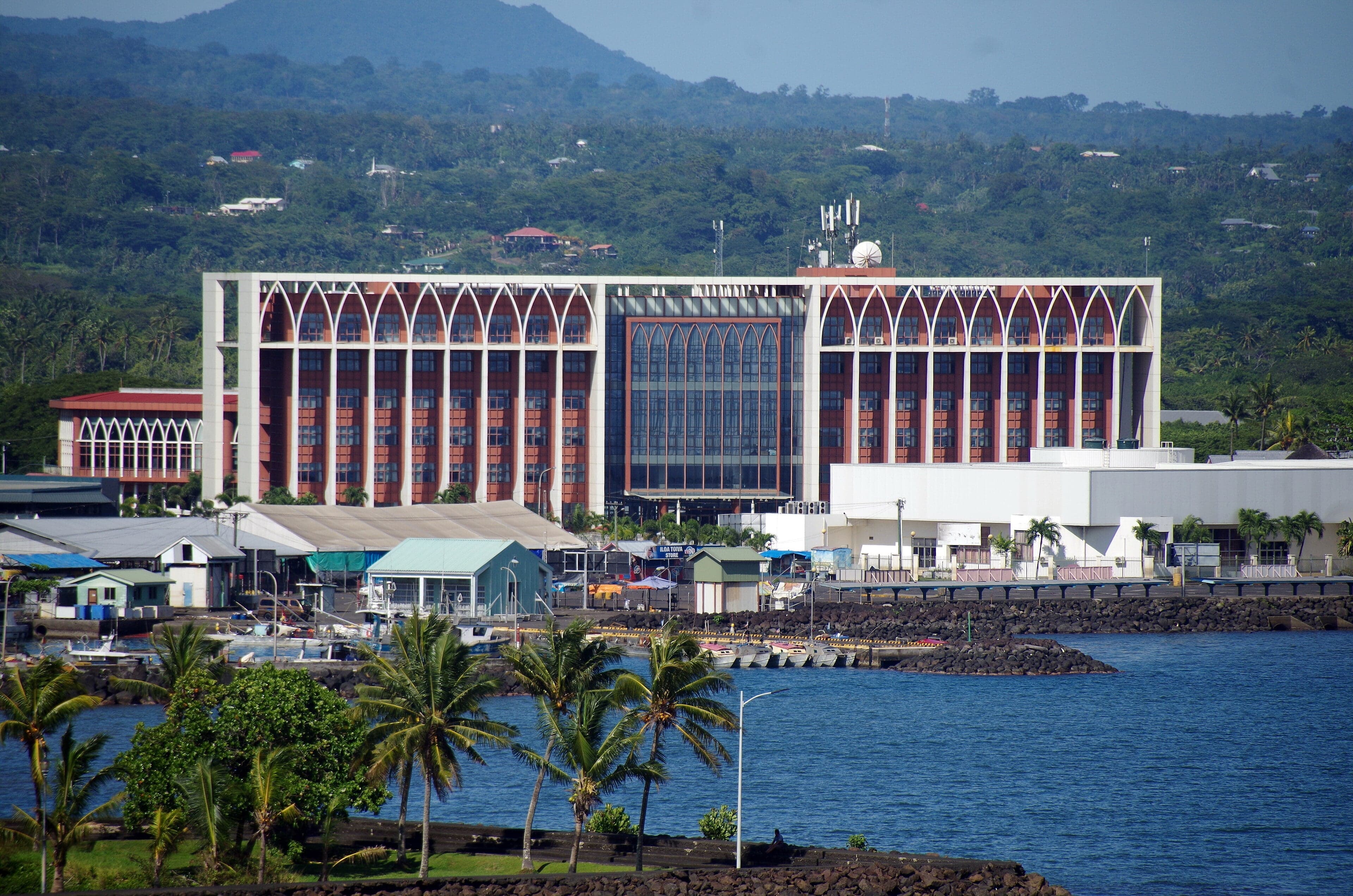 The colourful waterfront of Apia with boats in the harbour and palm trees