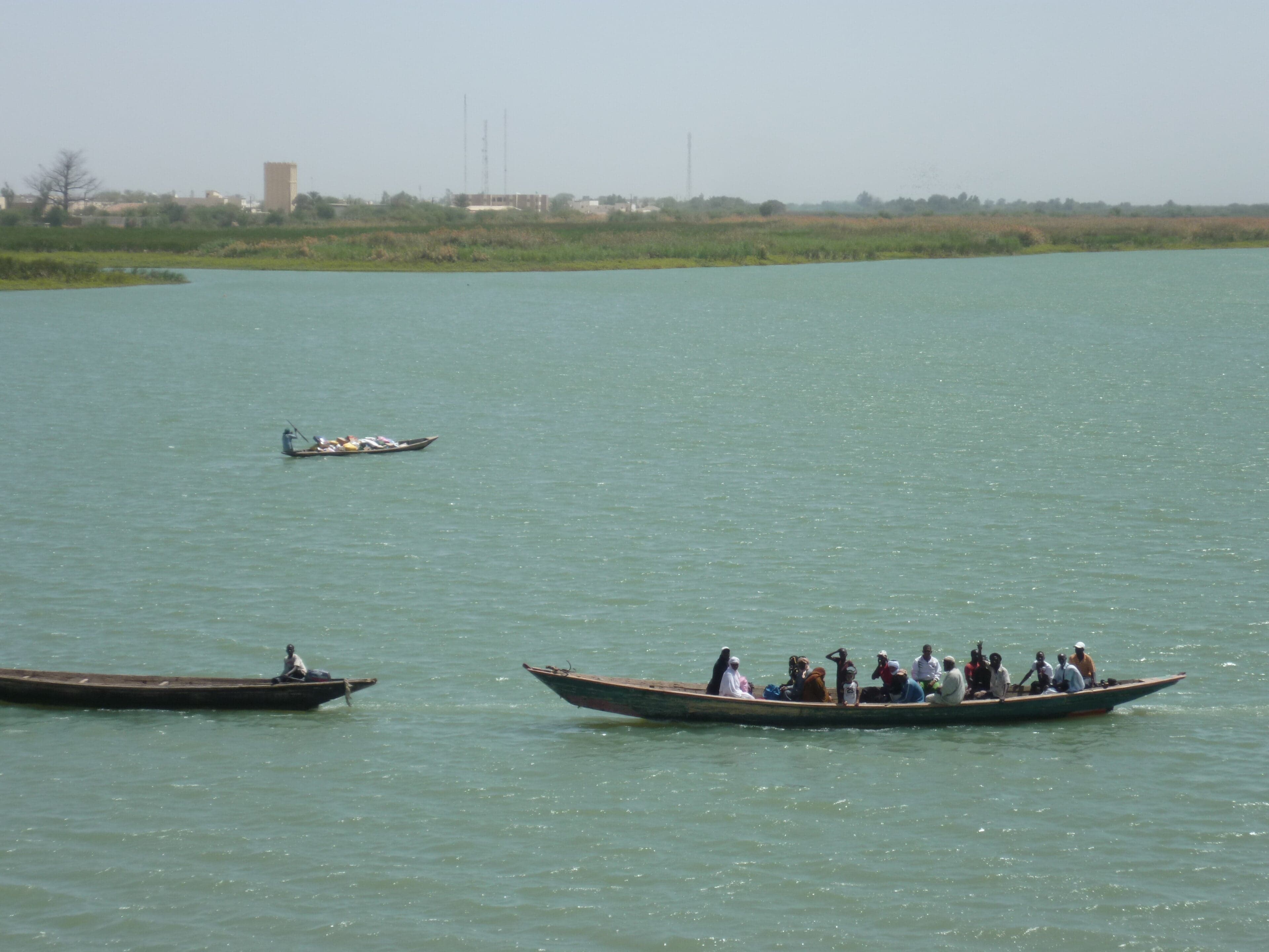 A wide stretch of the Senegal River with boats and green banks