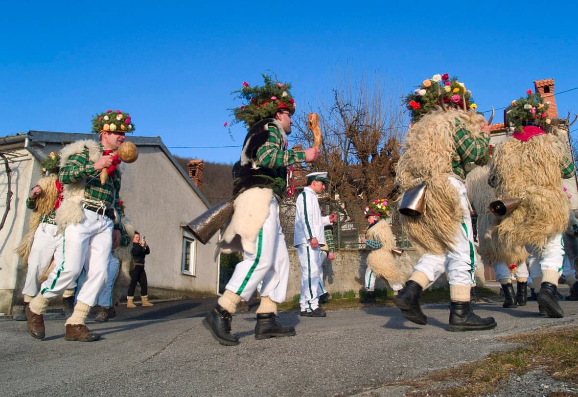 People in colourful Slovak Fašiangy masks and costumes walking through a village