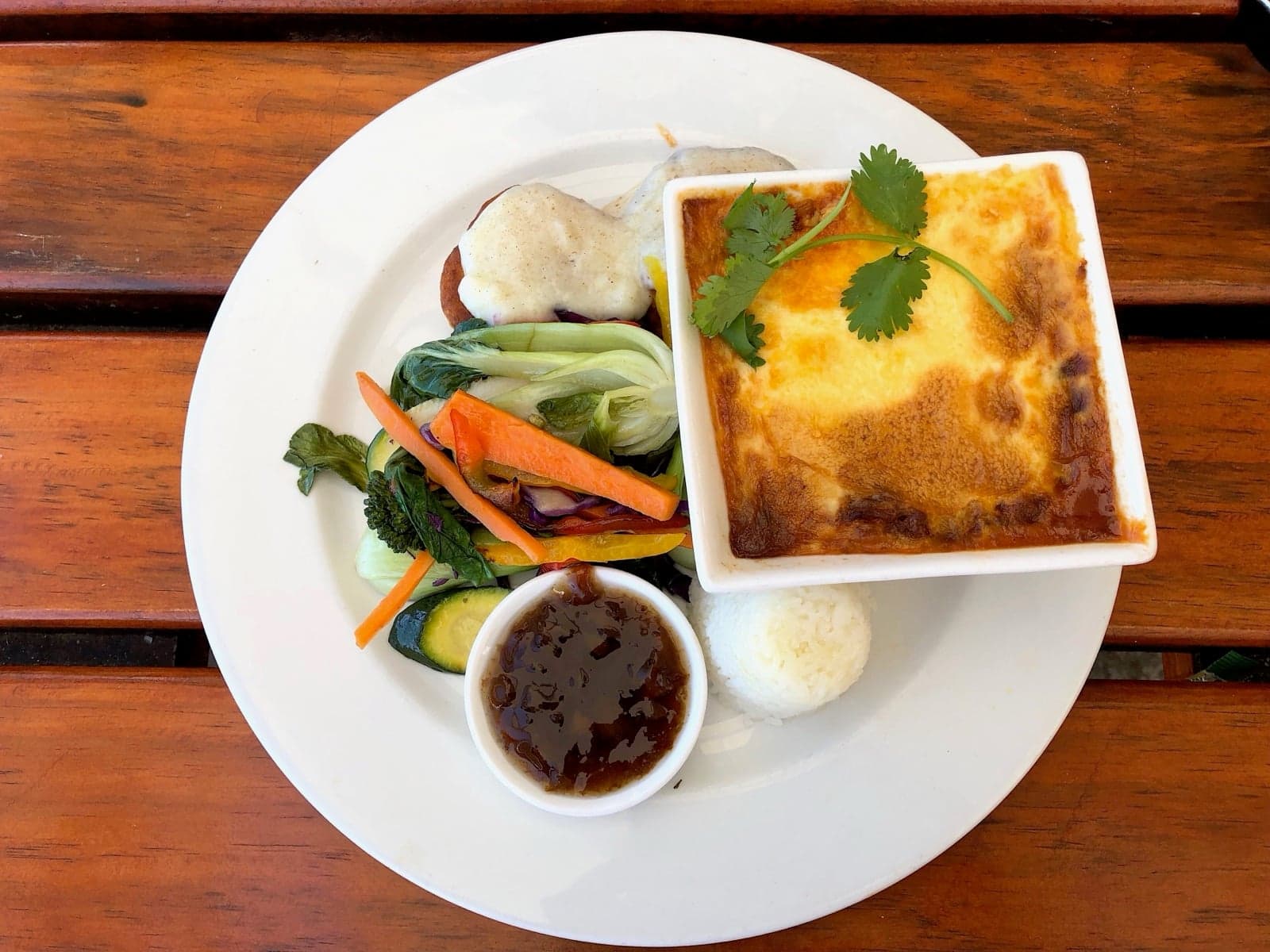 A baked bobotie served in a square dish with rice and salad