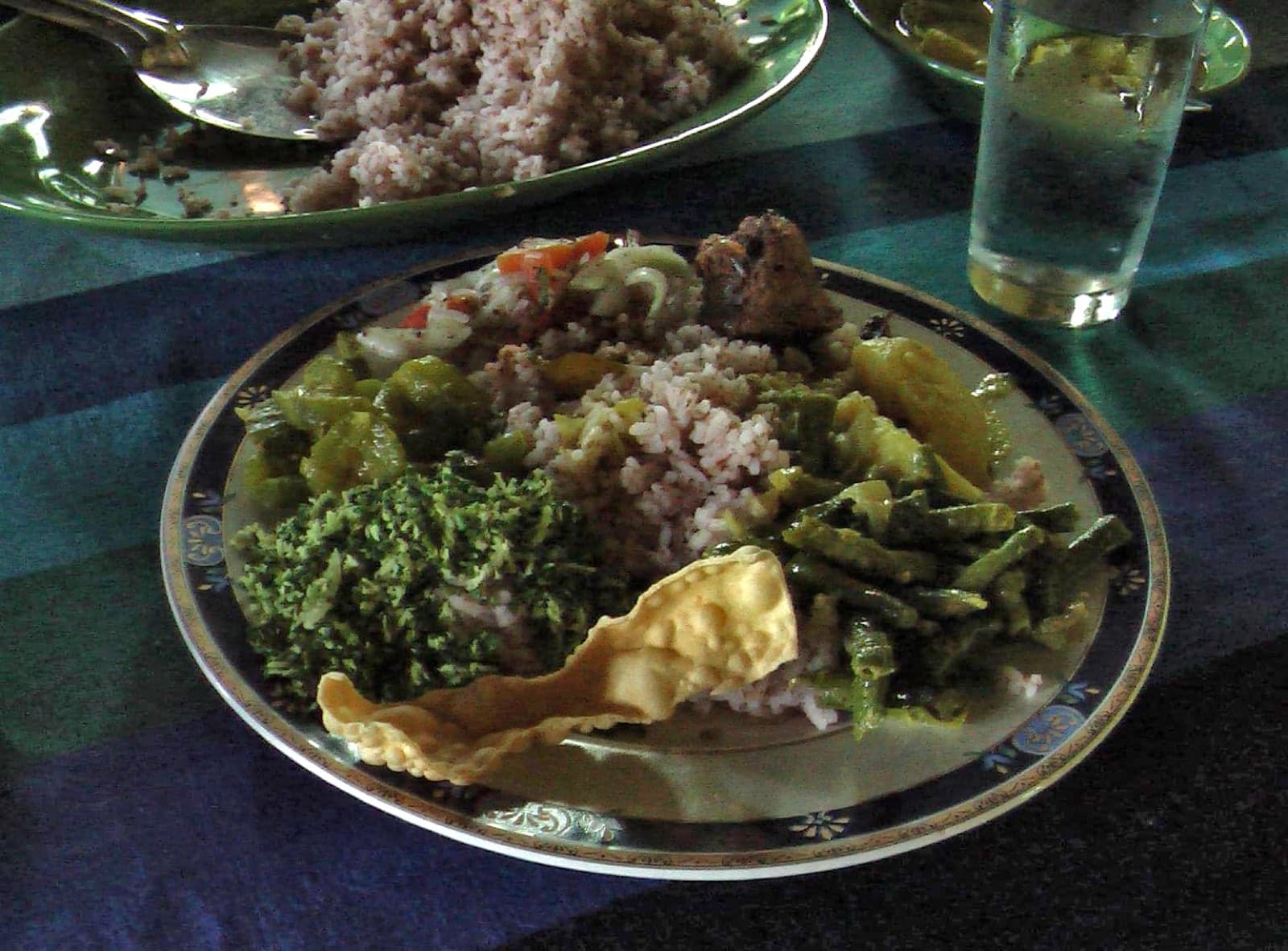 A Sri Lankan rice and curry meal: red rice surrounded by vegetable curries and a pappadam