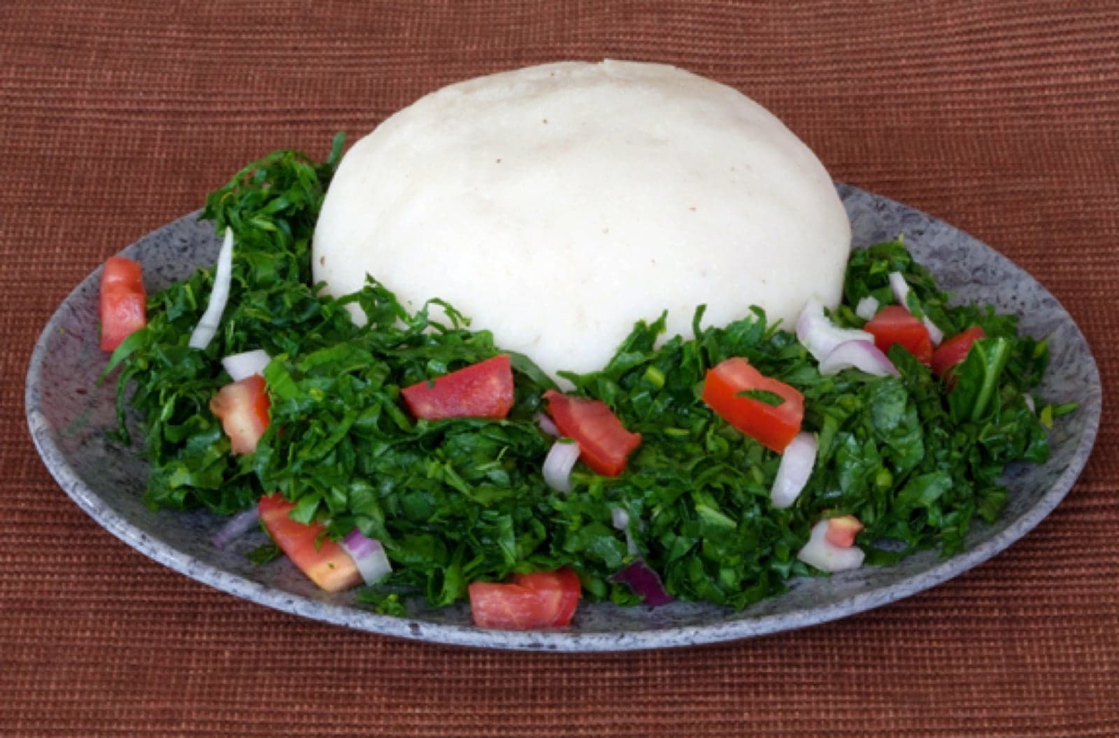 A plate of ugali served alongside vegetable stew