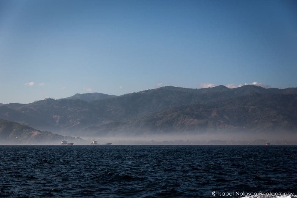 Dili harbour with boats on the water and the mountains visible behind the city