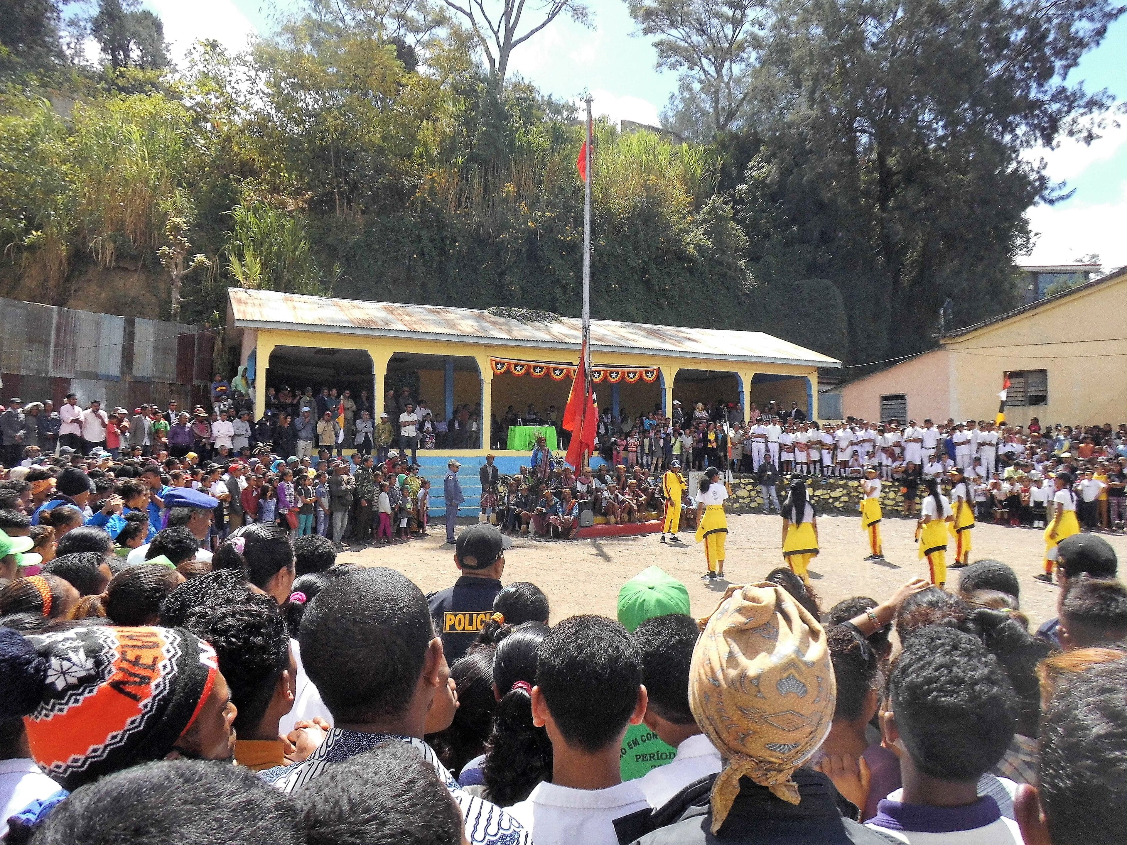 People celebrating Independence Restoration Day with flags and dancing in Dili
