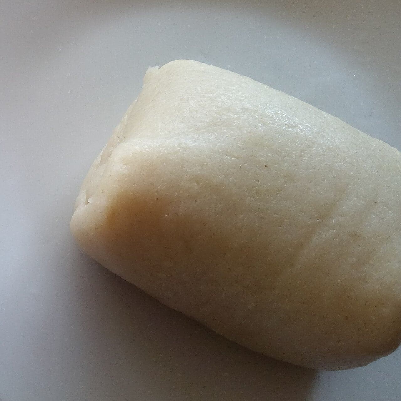 A round ball of smooth white akoumé cornmeal porridge on a banana leaf with sauce