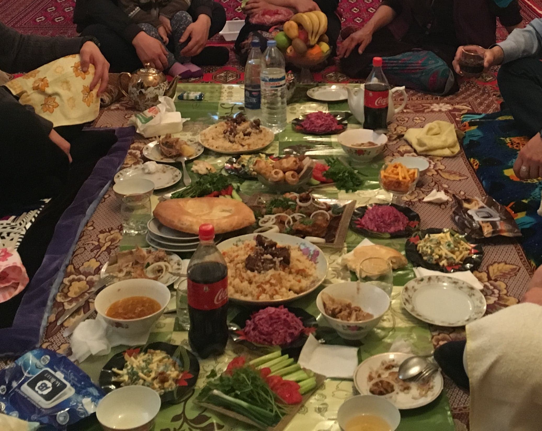 A plate of large steamed manty dumplings with a small bowl of yoghurt dipping sauce