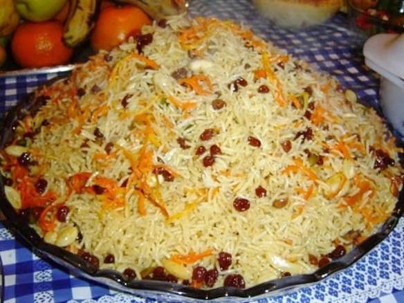A large round dish of golden plov - rice with lamb, carrots and onions - garnished with herbs