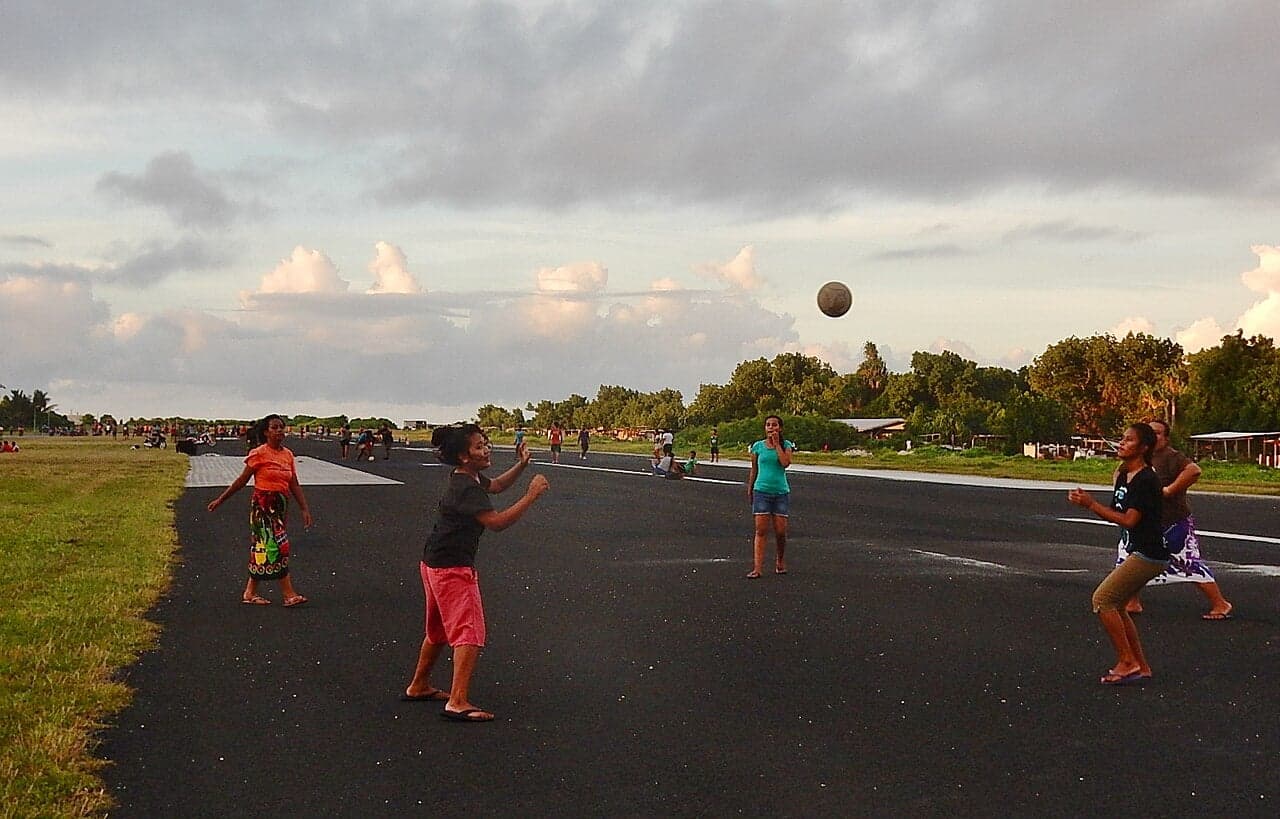 Children and families on a wide flat runway with the Pacific Ocean visible on each side