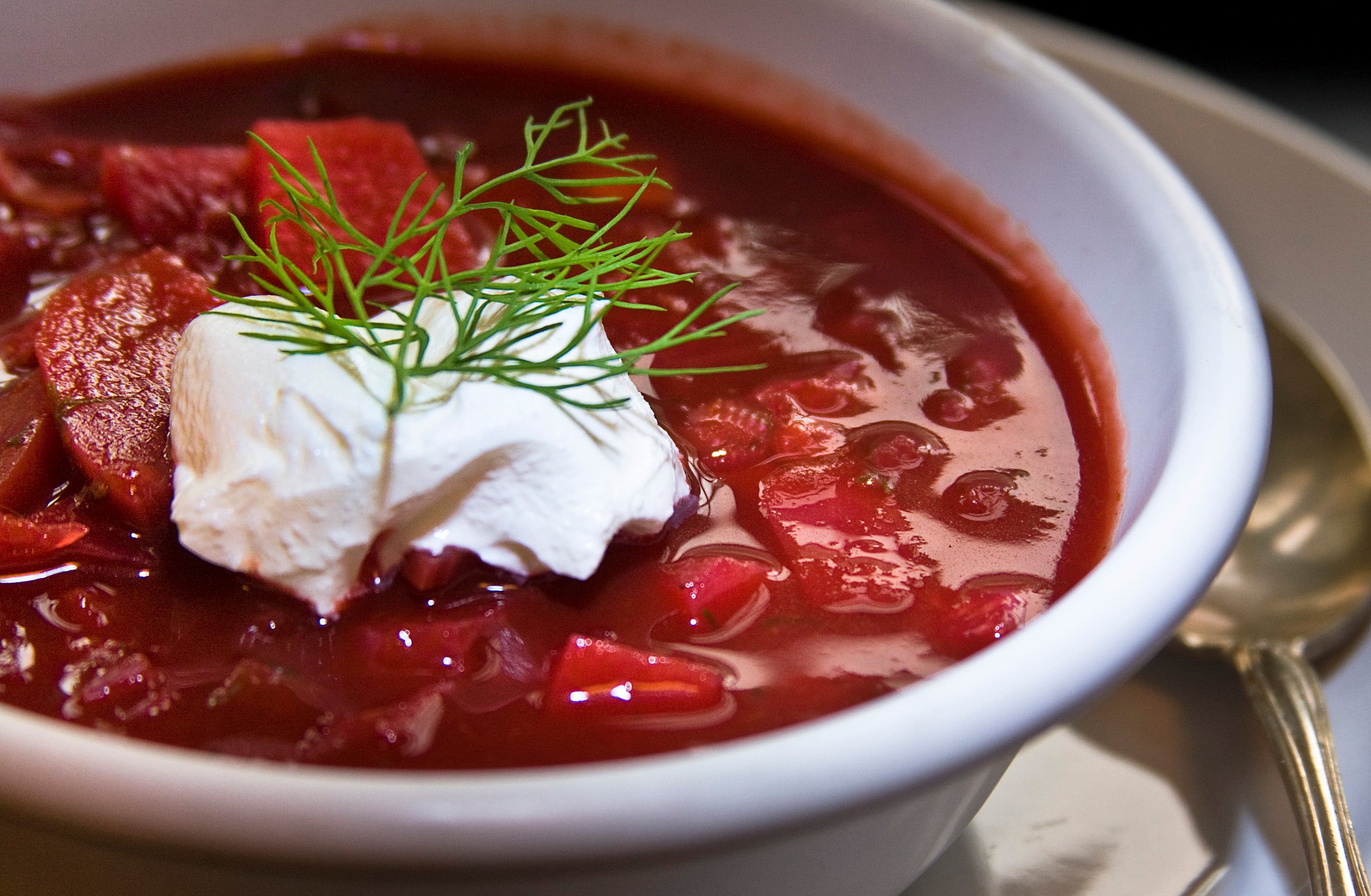 A bowl of bright pink borscht with a spoon of sour cream on top