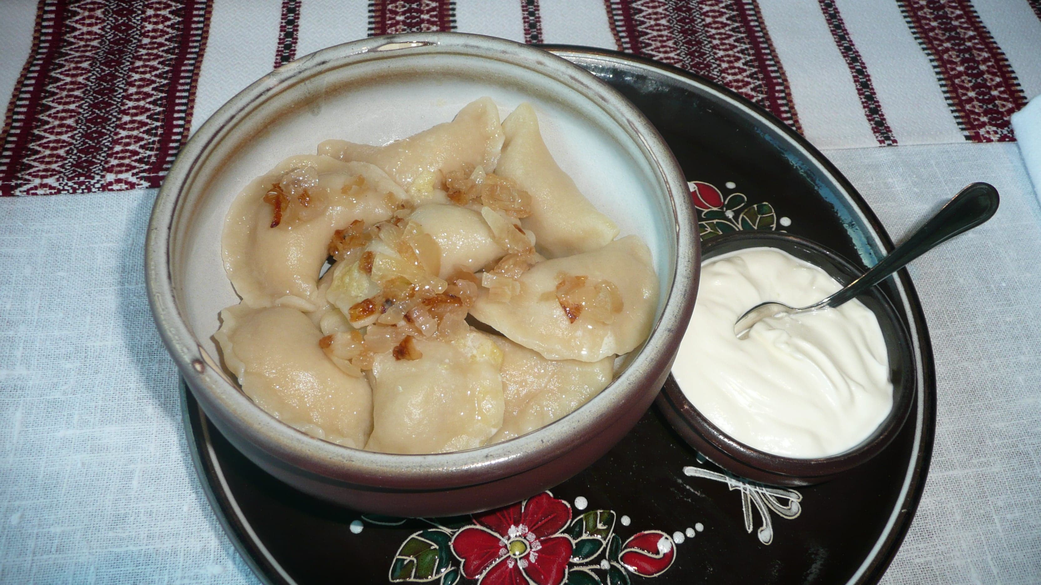A plate of varenyky dumplings topped with sour cream