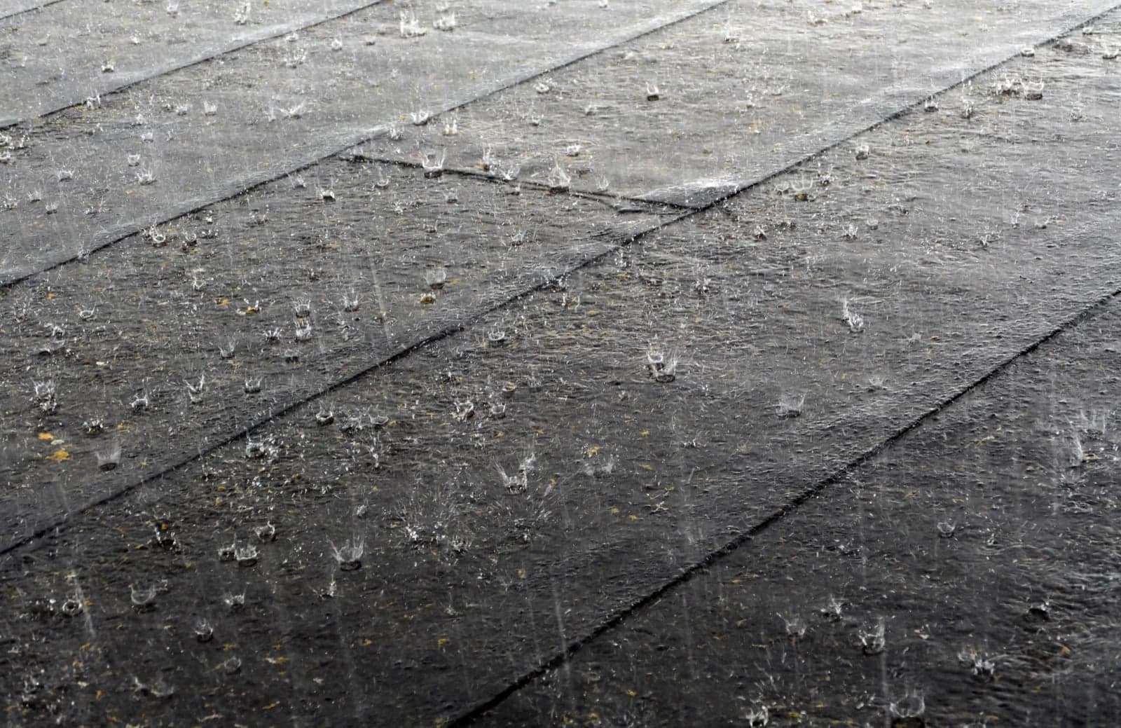 Rain falling hard onto a wet roof, drops bouncing