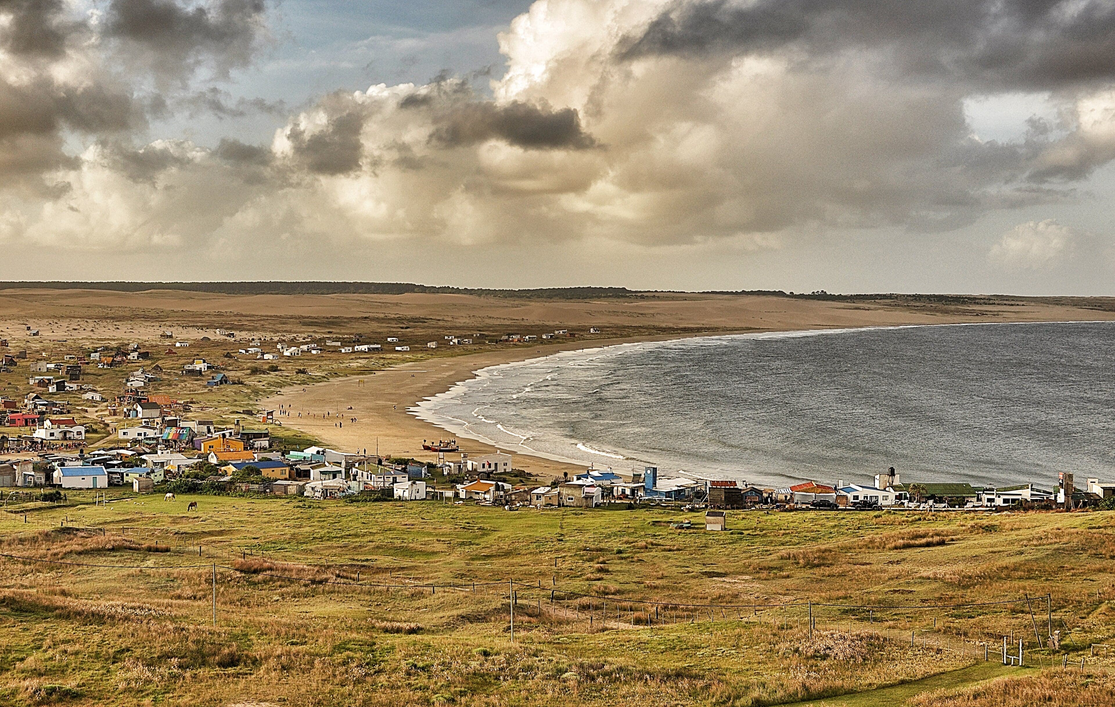 The lighthouse of Cabo Polonio rising above brightly painted wooden houses on the dunes