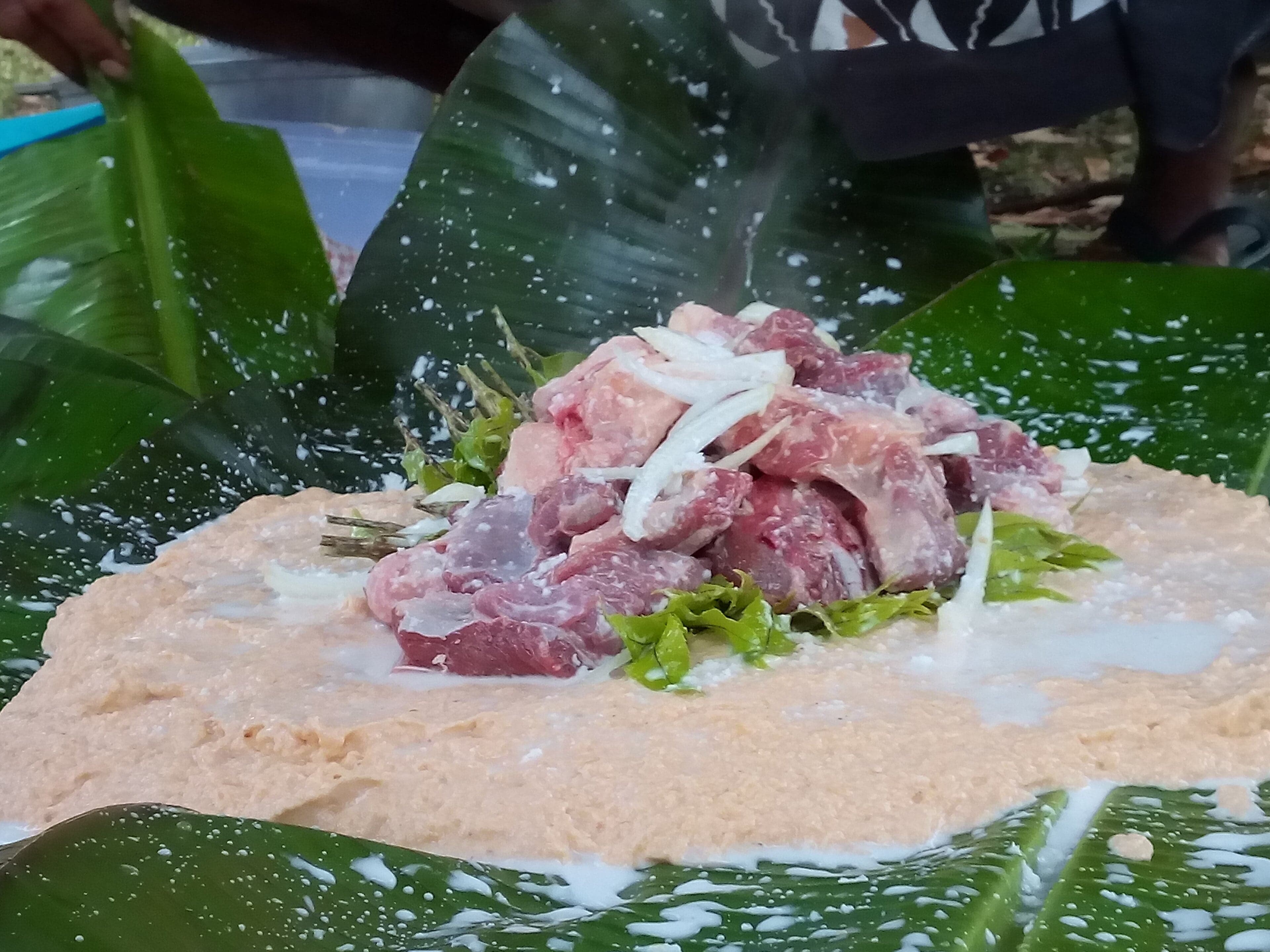 Lap lap wrapped in banana leaves being cooked on hot stones, Vanuatu
