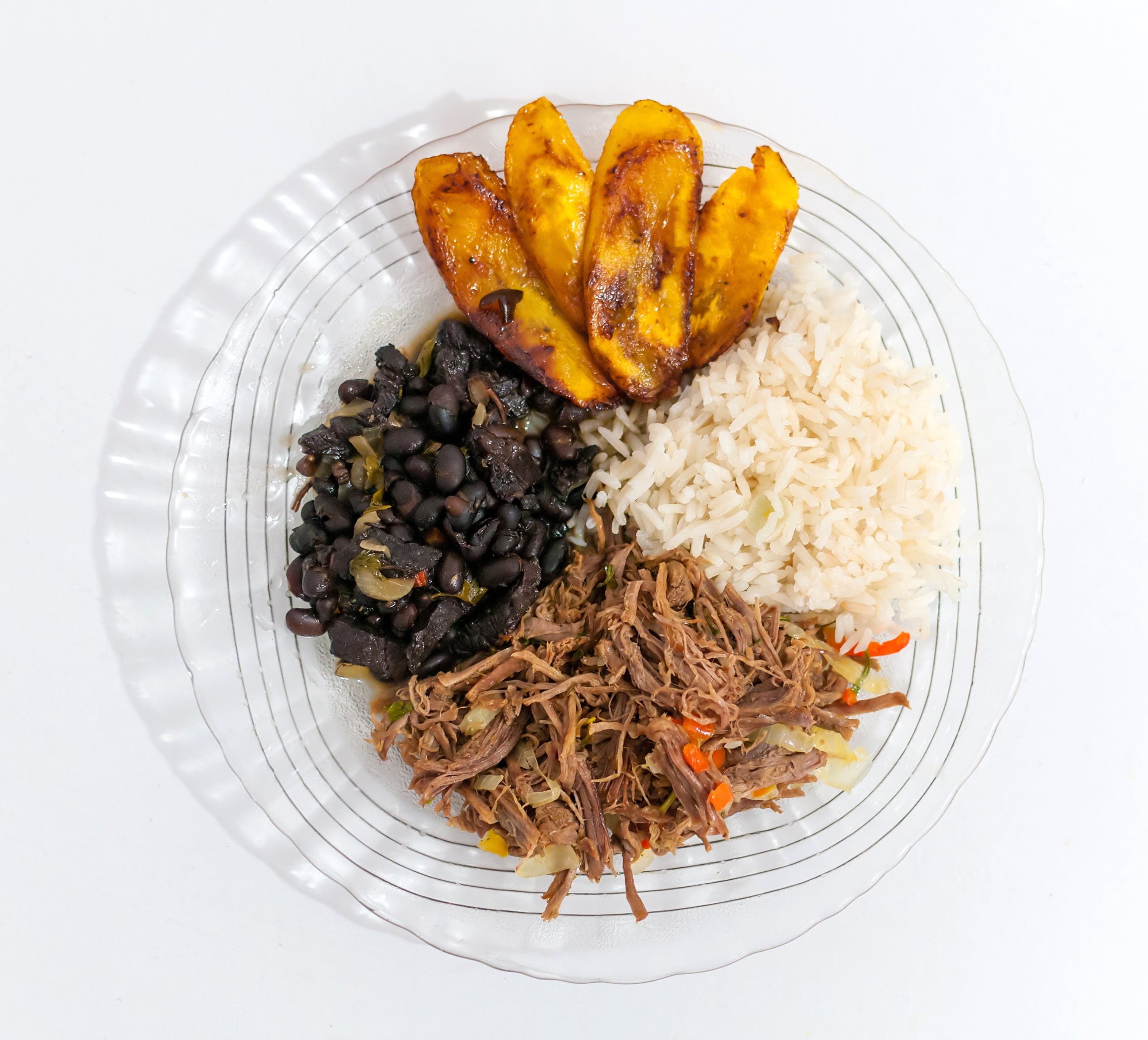 A plate of Venezuelan pabellón criollo with rice, black beans, shredded beef and plantain