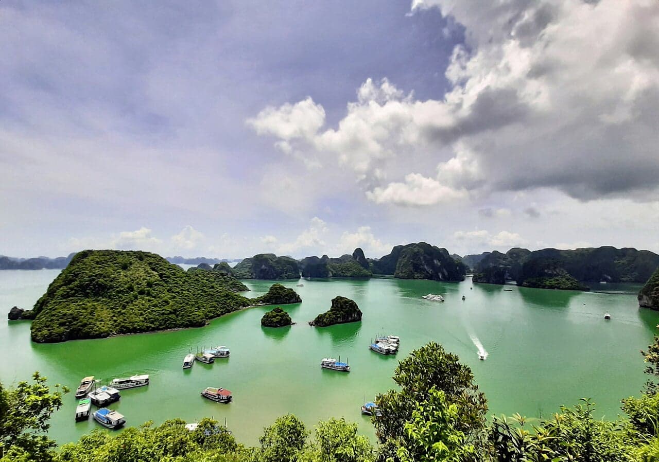 Ha Long Bay - dozens of forested limestone islands rising out of green-blue water, with small boats below