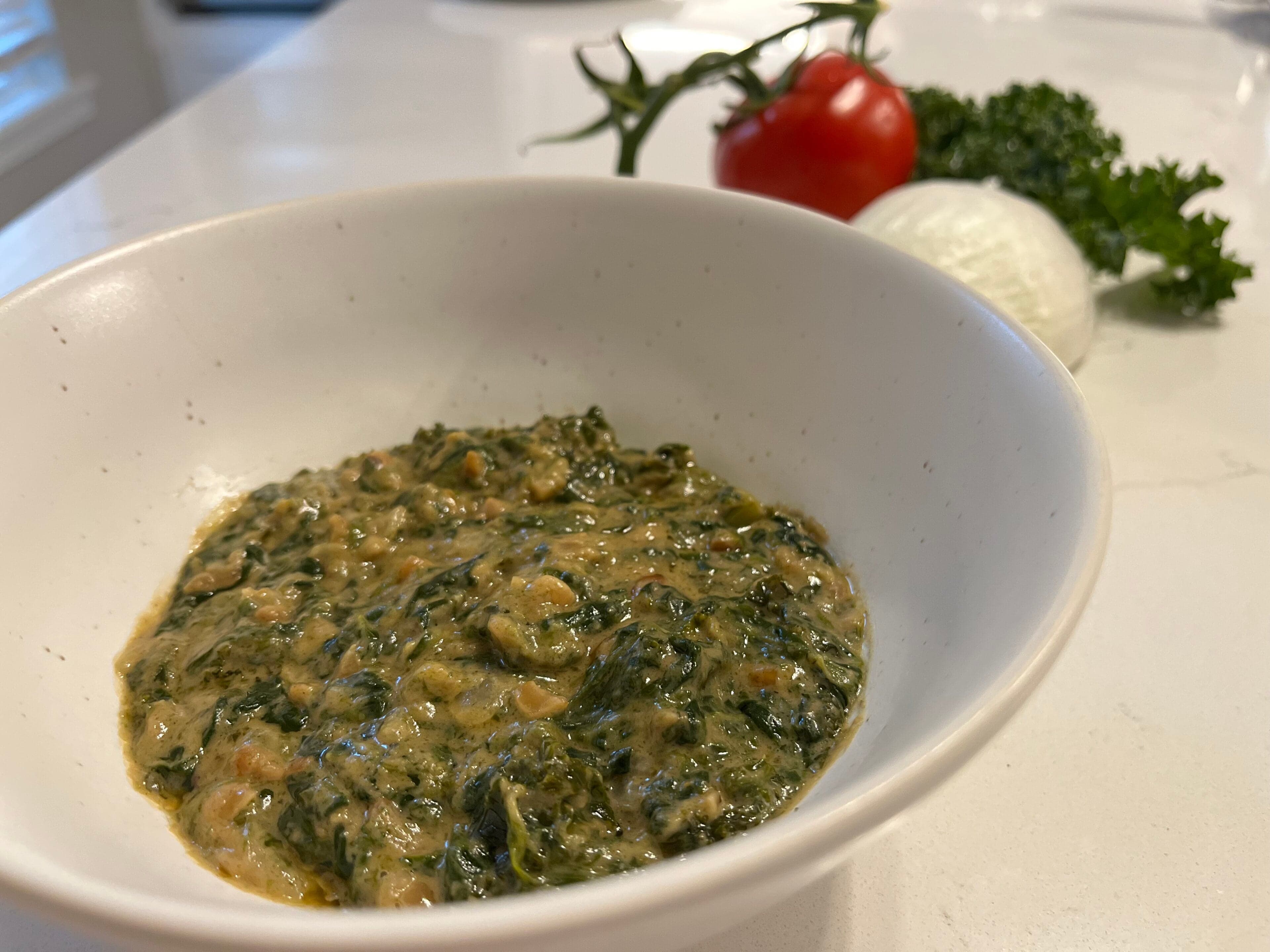 A bowl of dark green ifisashi made with leafy greens and groundnut sauce