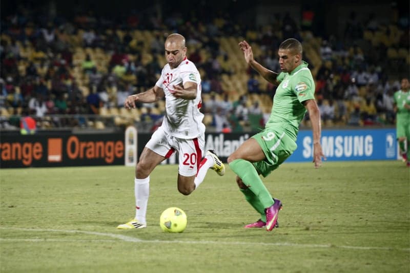 Algerian football fans waving green and white flags in a packed stadium