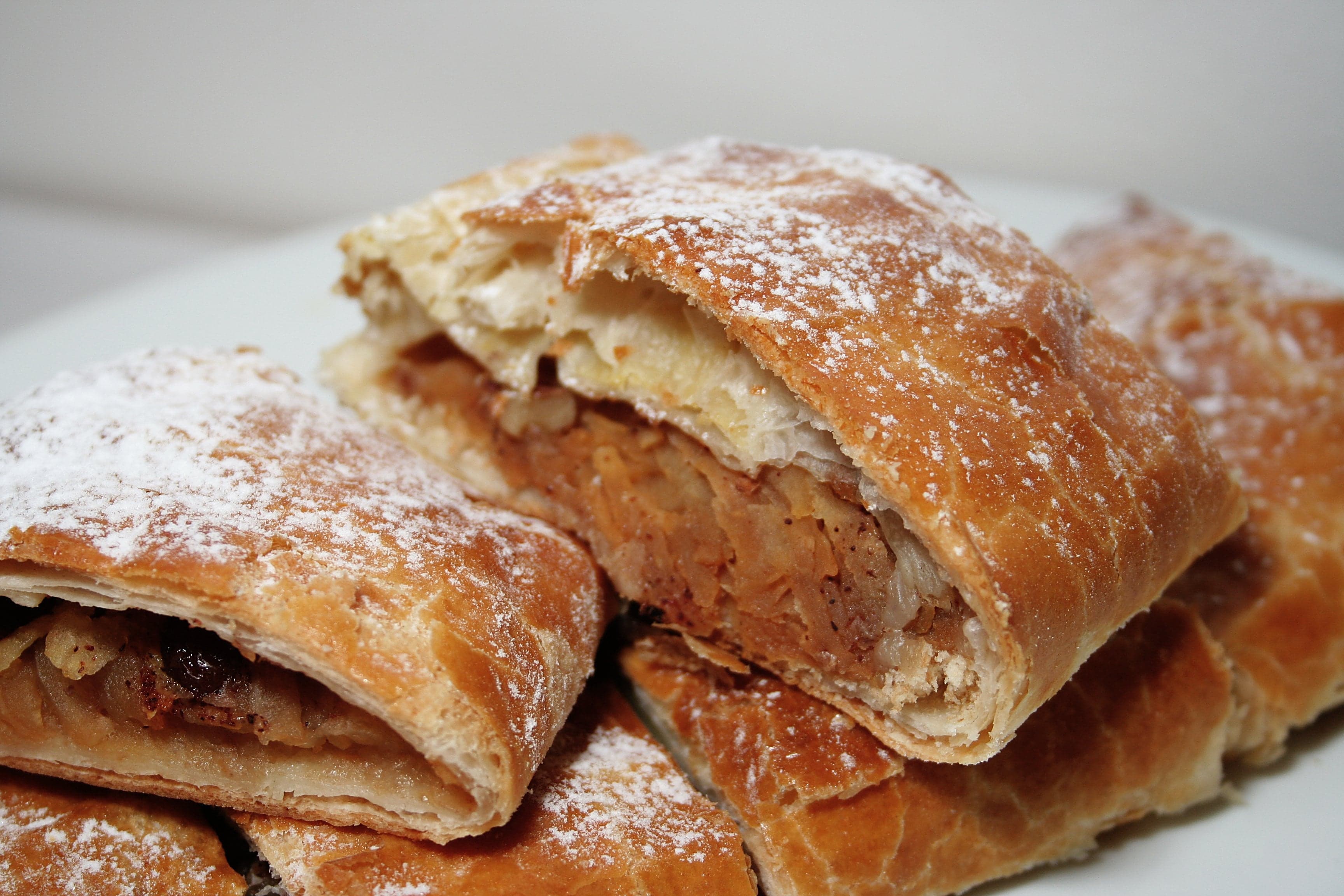 A slice of golden apfelstrudel dusted with icing sugar and served with vanilla sauce