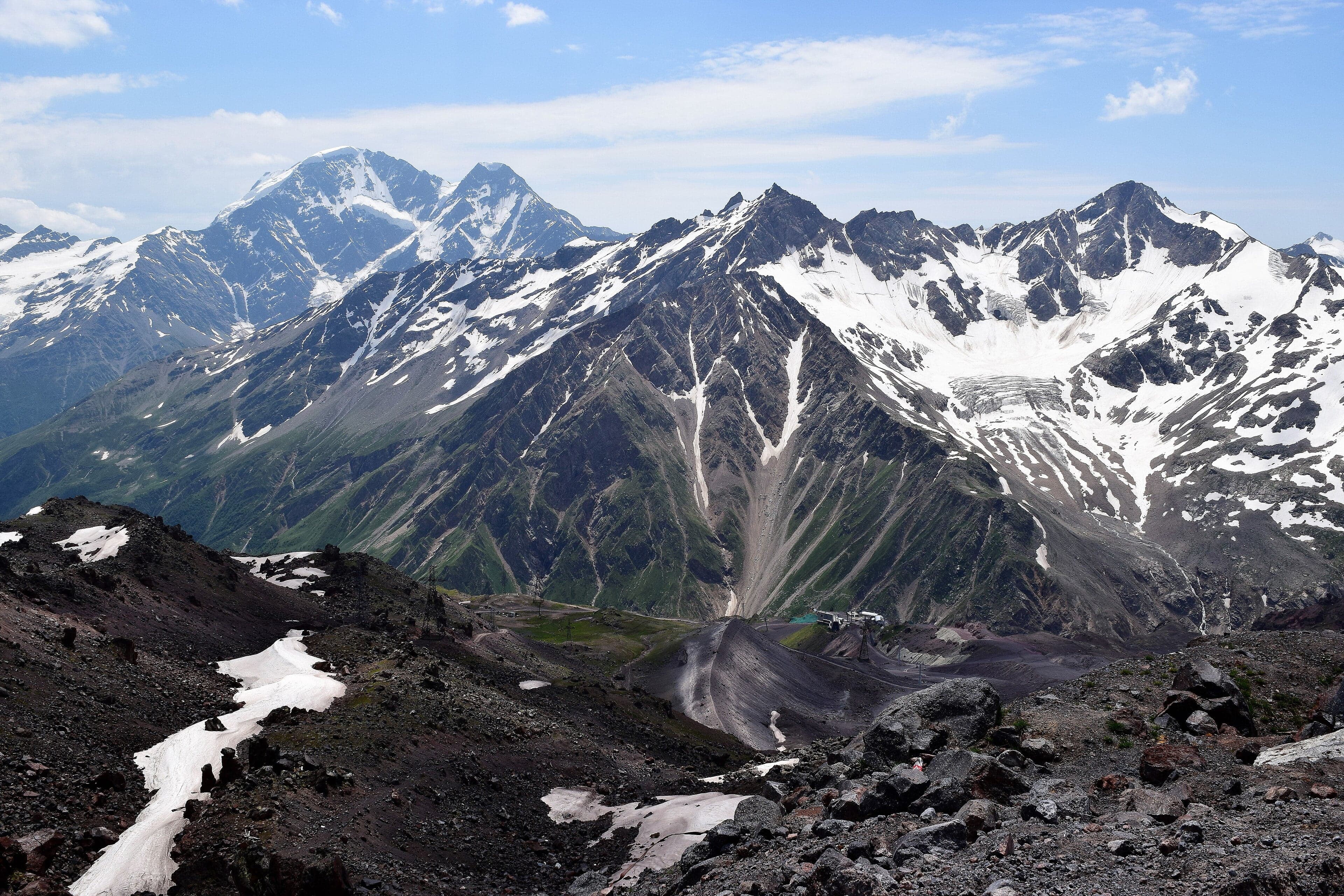 Snow-capped peaks of the Caucasus Mountains rising above a green valley in northern Azerbaijan