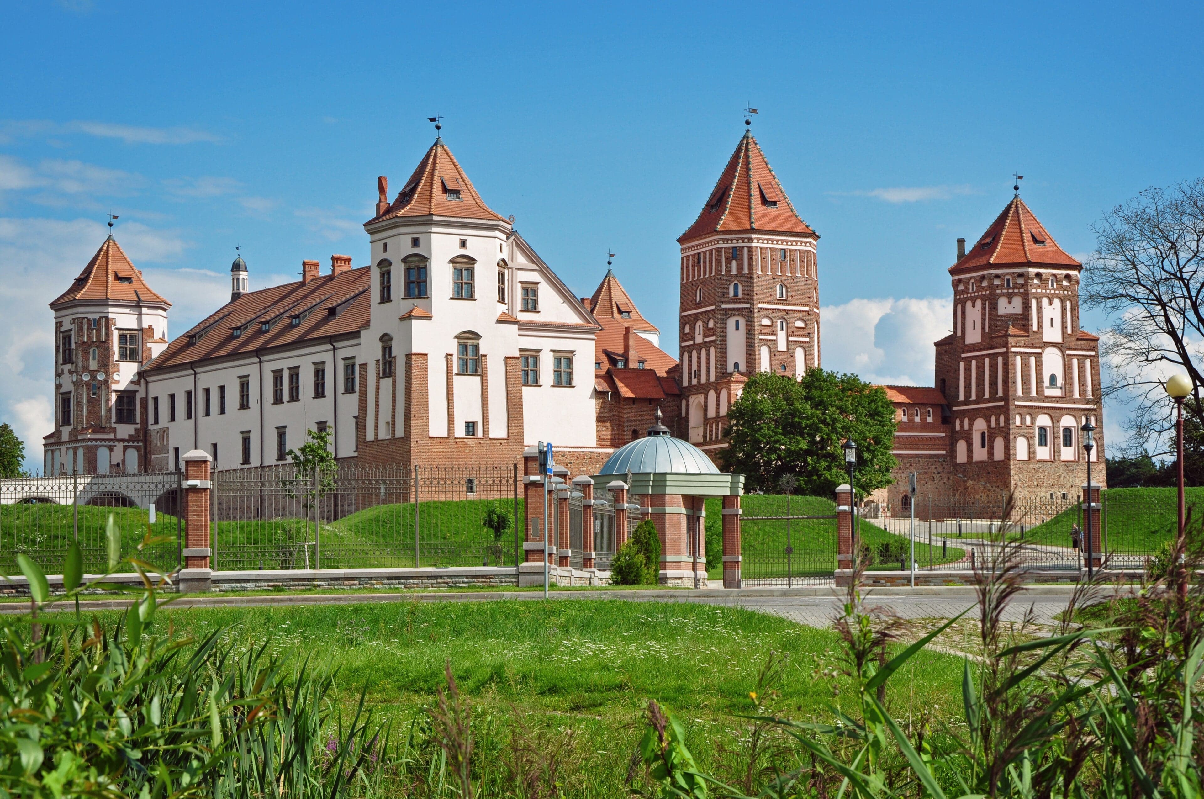 Mir Castle reflected in the still water of the surrounding moat on a clear day