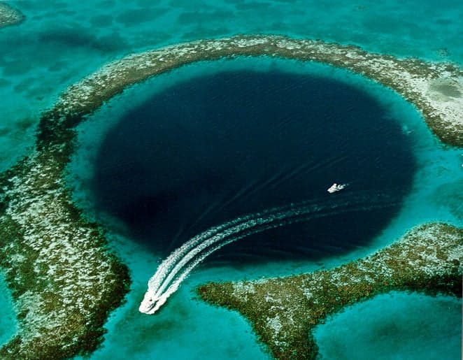 Aerial view of the Great Blue Hole - a perfect dark-blue circle surrounded by turquoise reef