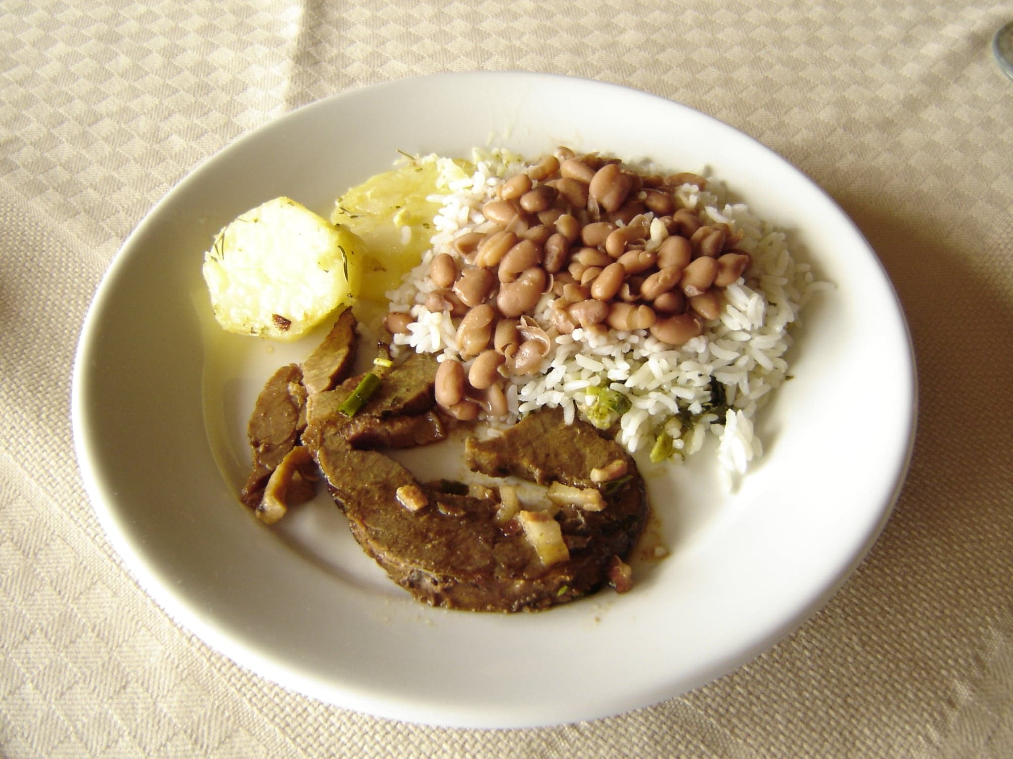 A colourful plate of red kidney beans cooked with rice, served with stewed chicken and coleslaw