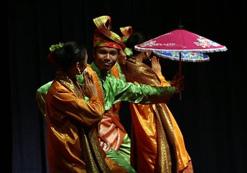 Two dancers in colourful traditional Malay costume performing the joget dance