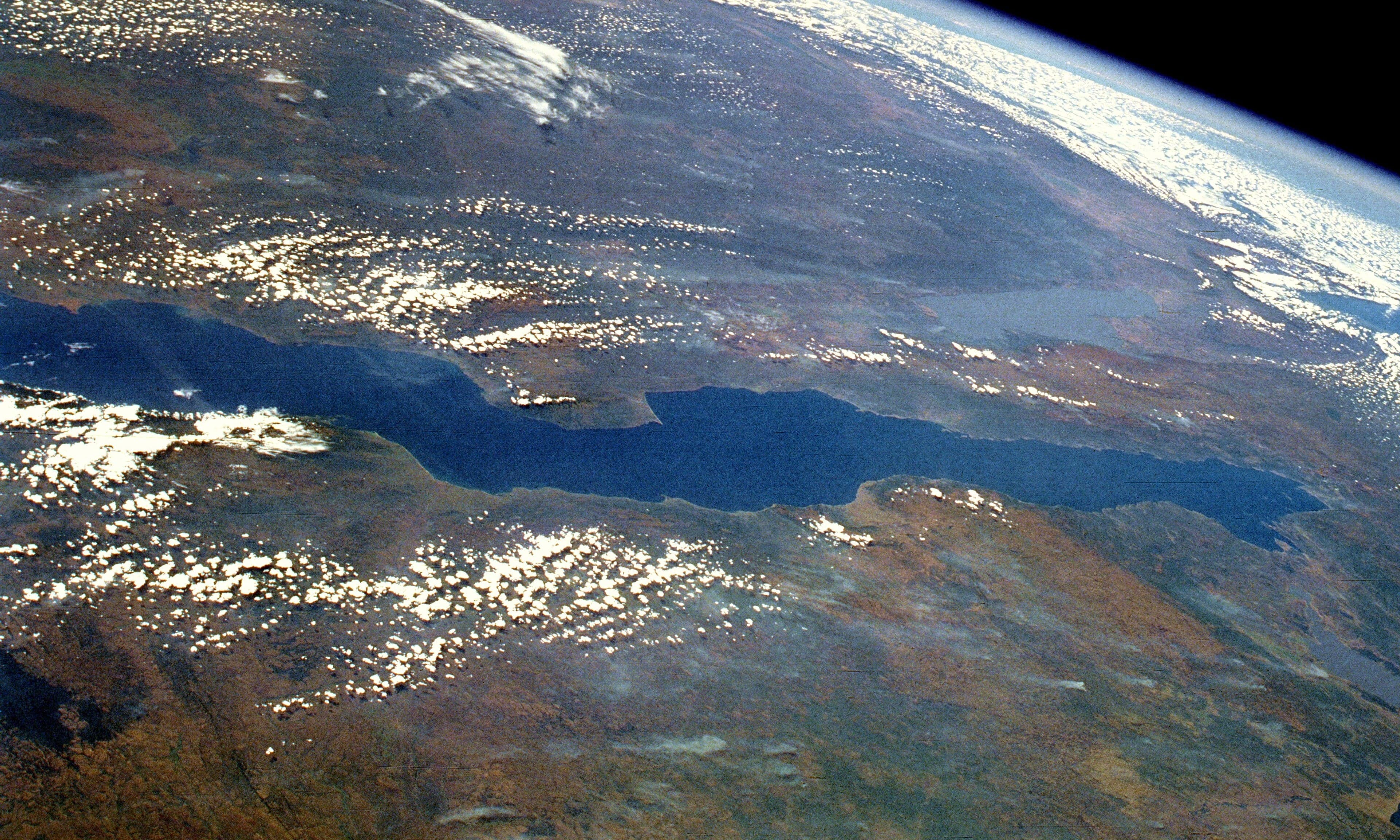 The calm blue surface of Lake Tanganyika with green hills behind it