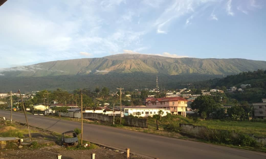 Mount Cameroon rising above green forest with cloud around its peak