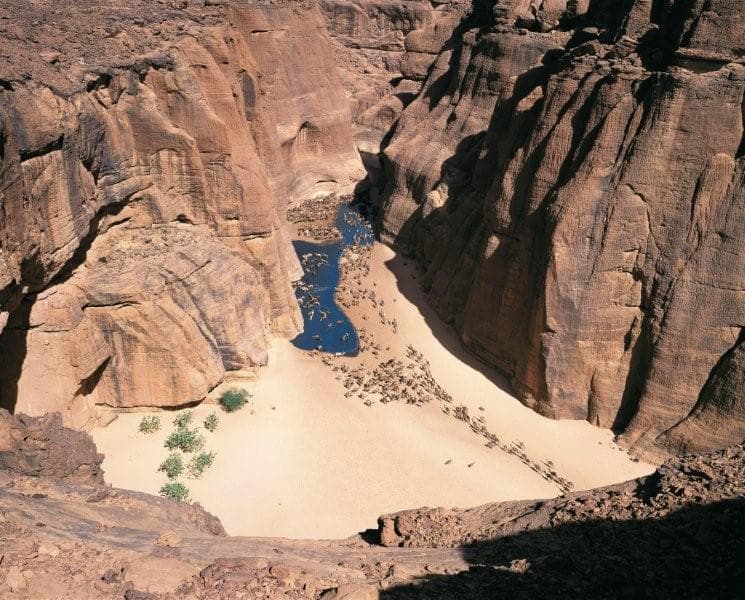Tall sandstone arches and towers rising out of the desert landscape of the Ennedi Plateau
