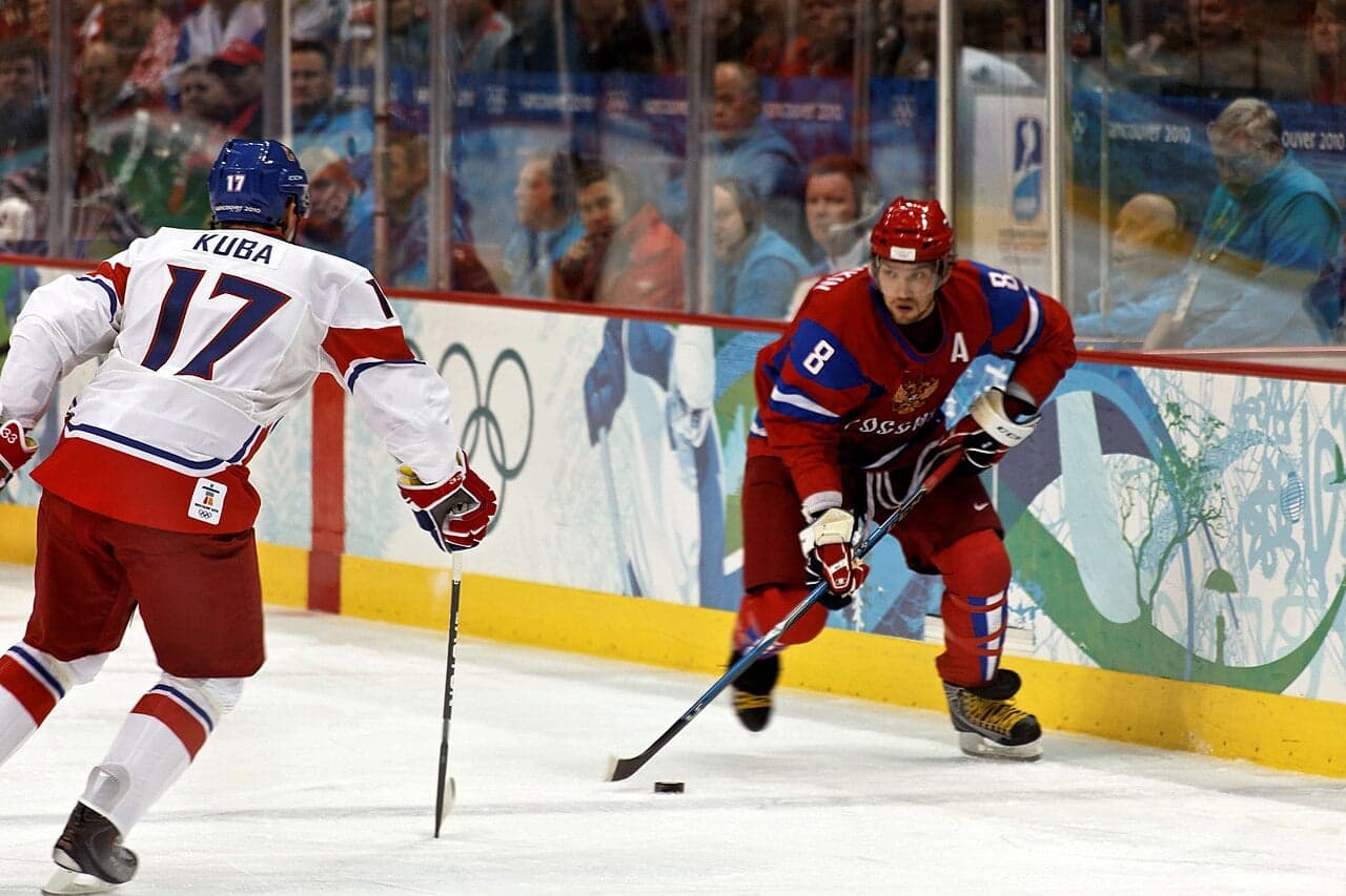 Czech ice hockey players in action on a rink, chasing the puck