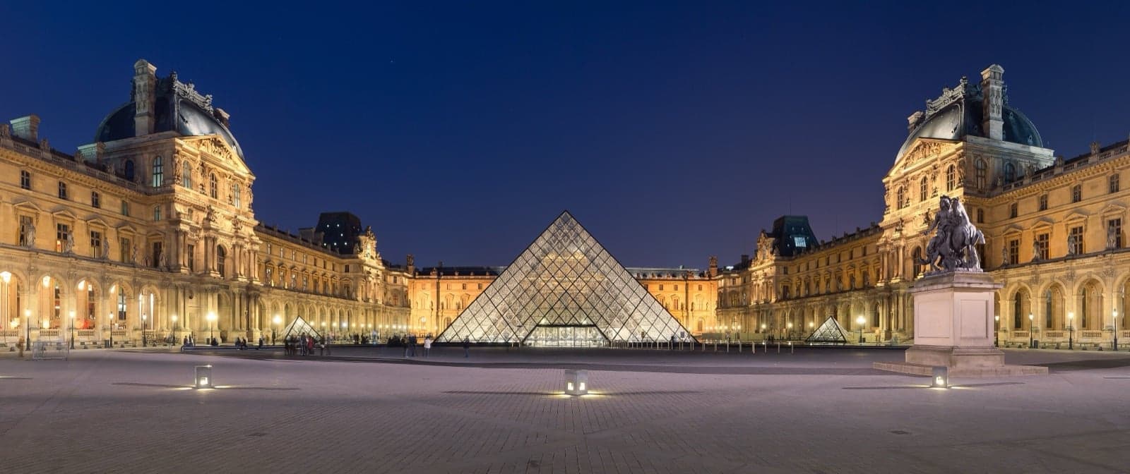 The Louvre at night with its famous glass pyramid in the courtyard