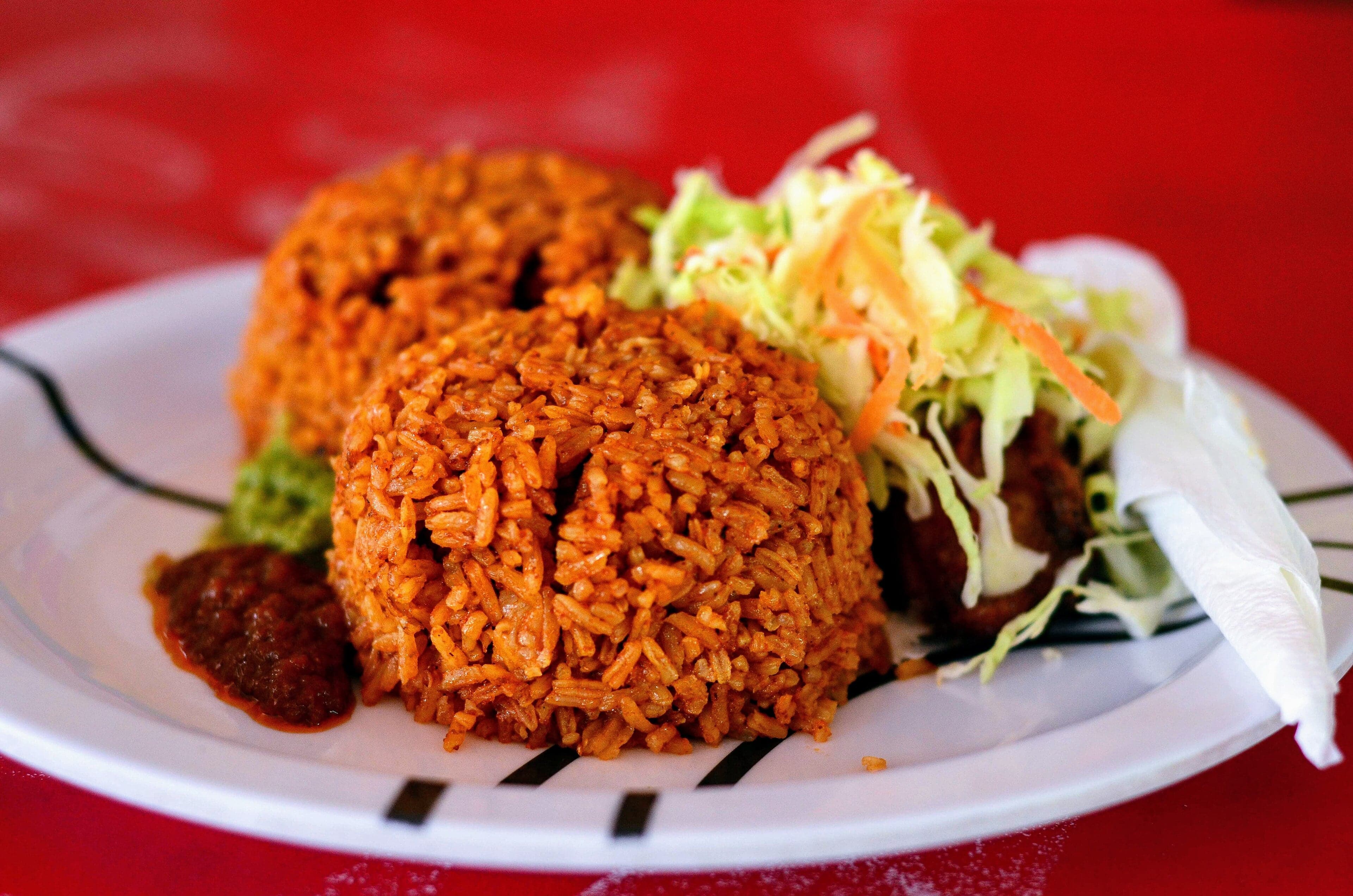 A colourful pot of benachin jollof rice with vegetables and fish on top