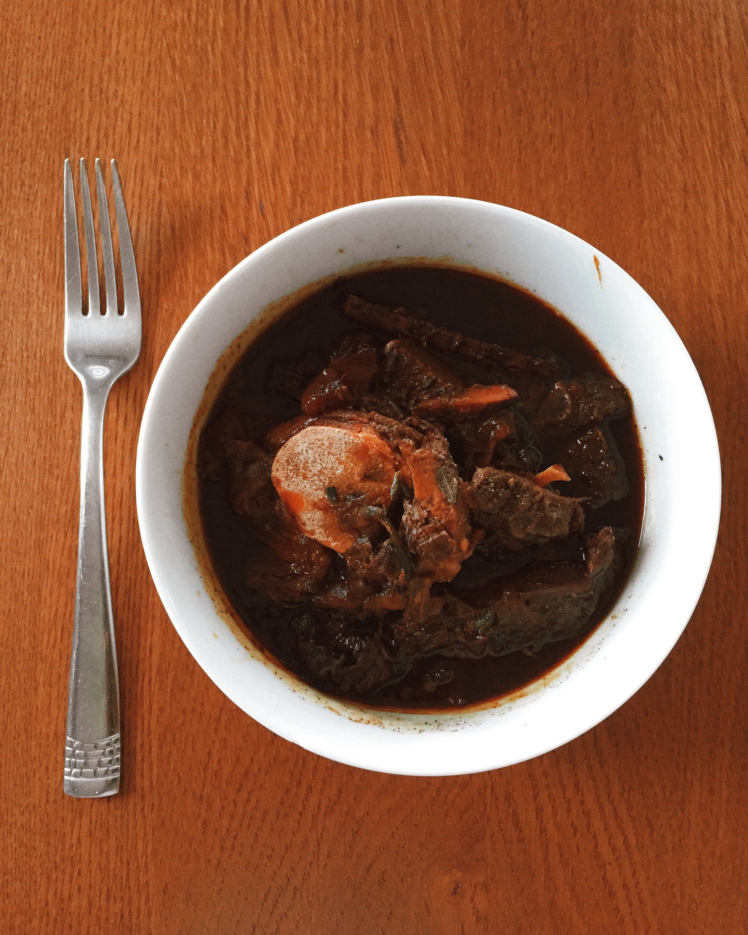 A pot of Guyanese pepperpot stew with chunks of meat in dark cassareep sauce