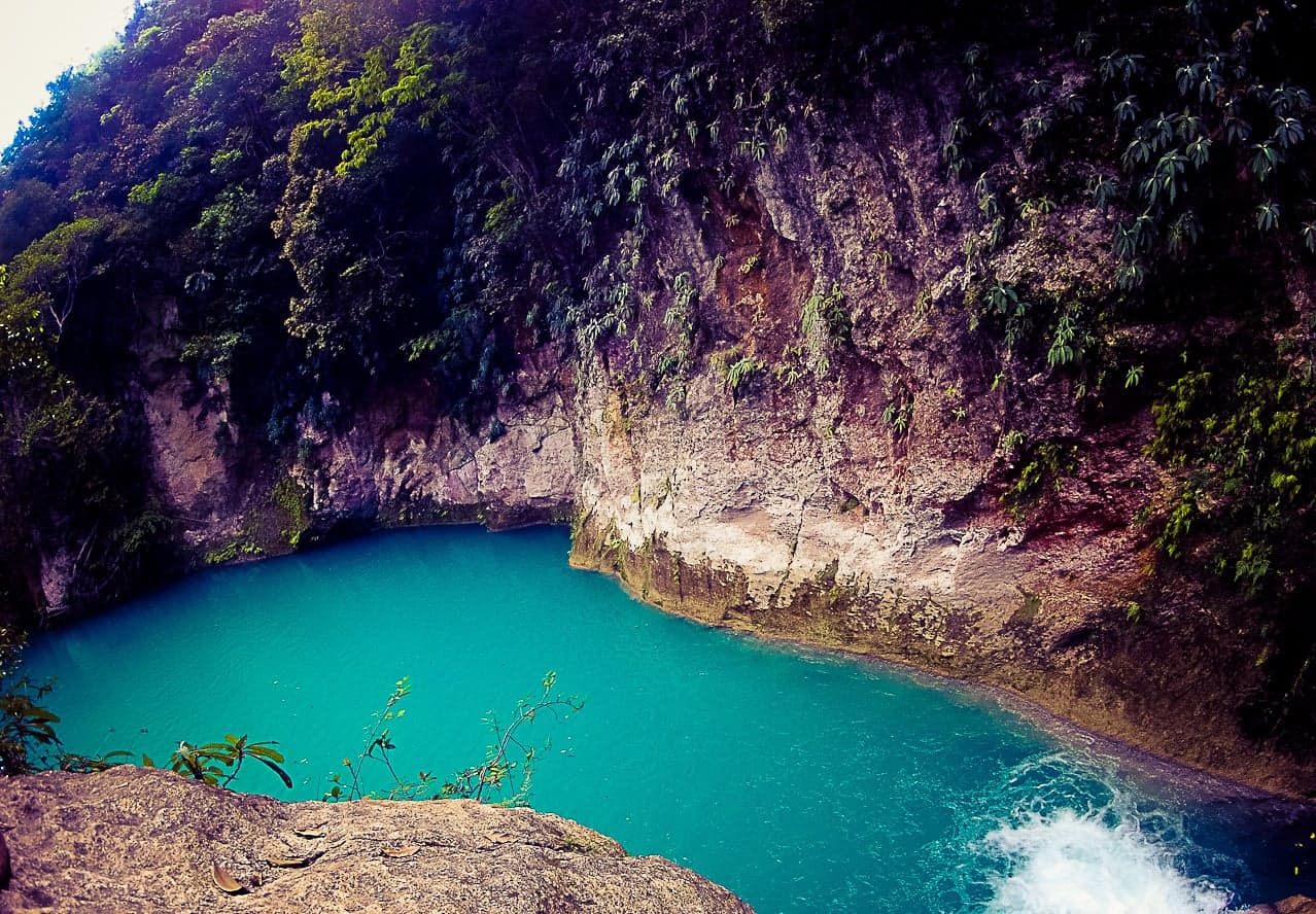 A stunning turquoise pool surrounded by lush green cliffs at Bassin Bleu