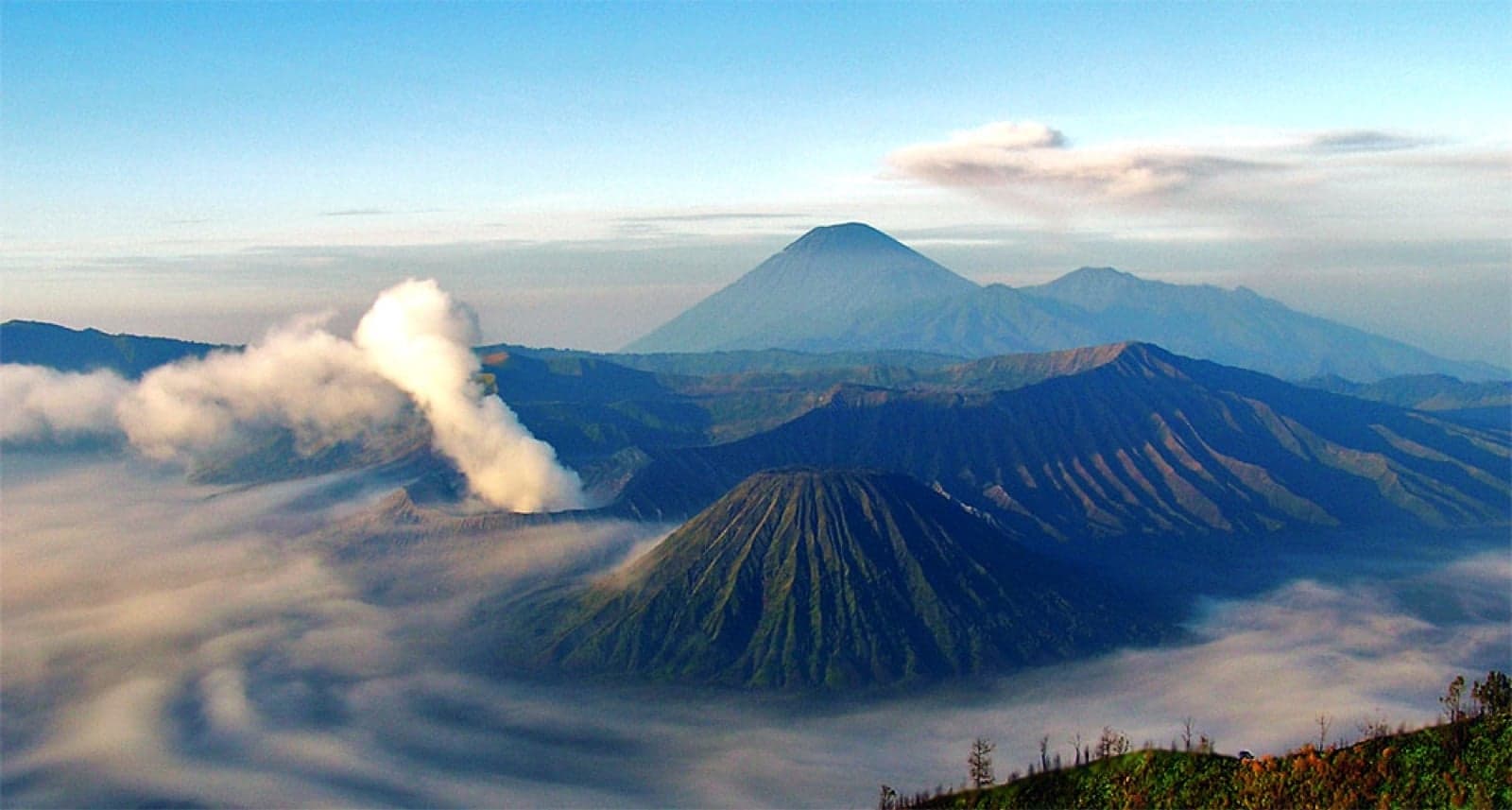 Mount Bromo at sunrise, with mist drifting around the volcanic cones in Java